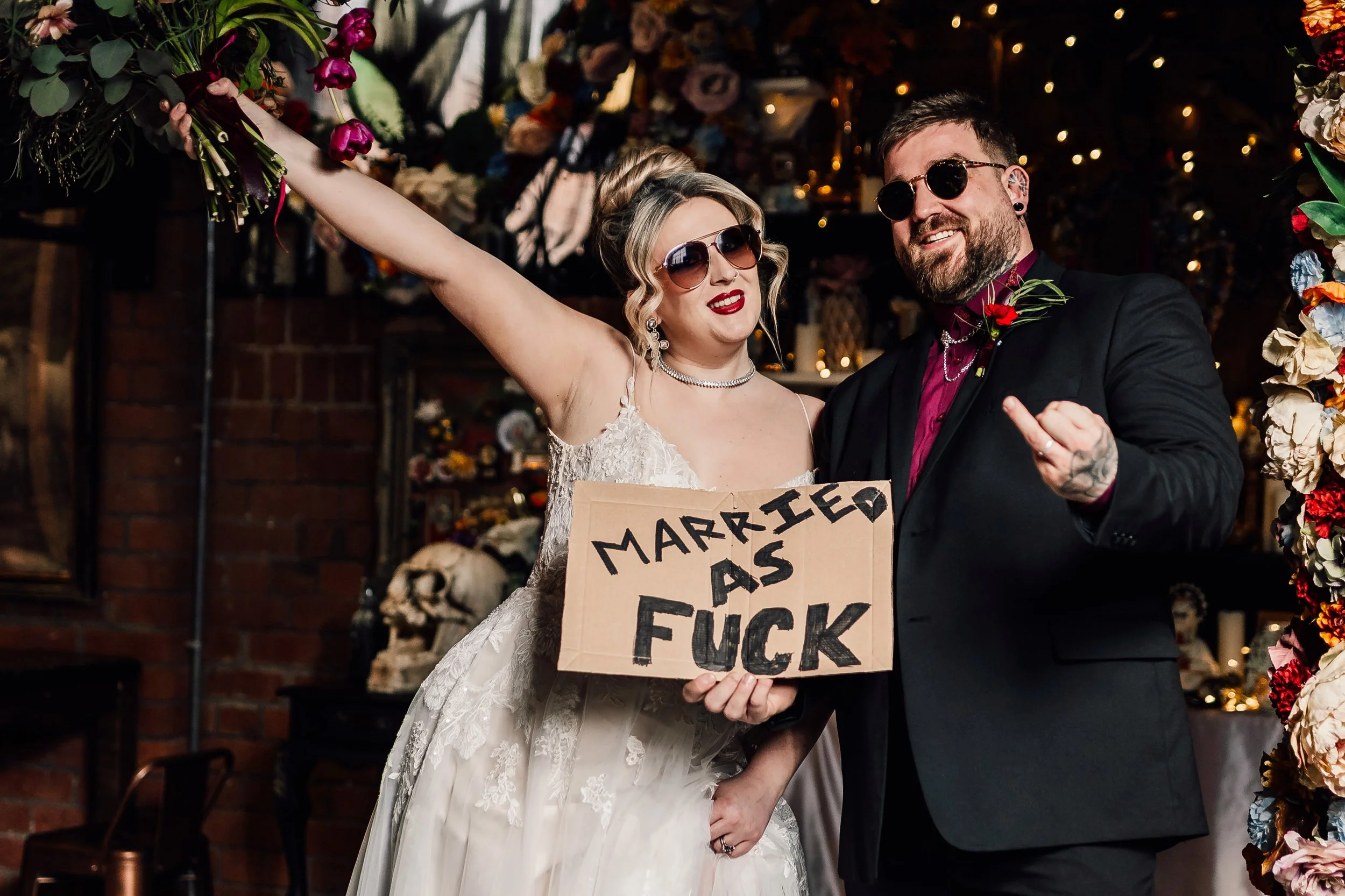 Fun alternative wedding couple with bold “married as fuck” sign at Church Temple of Fun wedding venue Sheffield