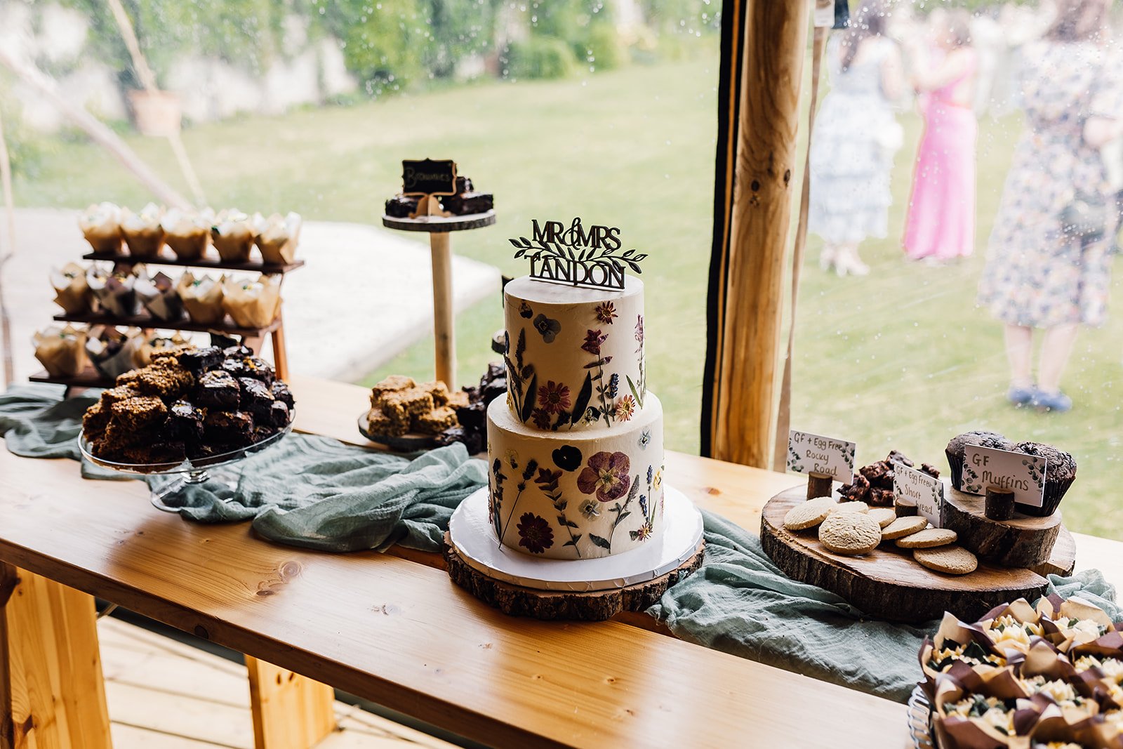 Wedding cake and cupcakes displayed on a wooden table at Scrivelsby Walled Garden