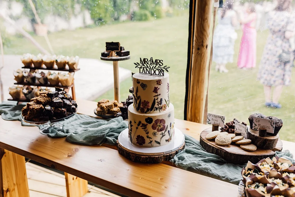 Wedding cake and cupcakes displayed on a wooden table at Scrivelsby Walled Garden