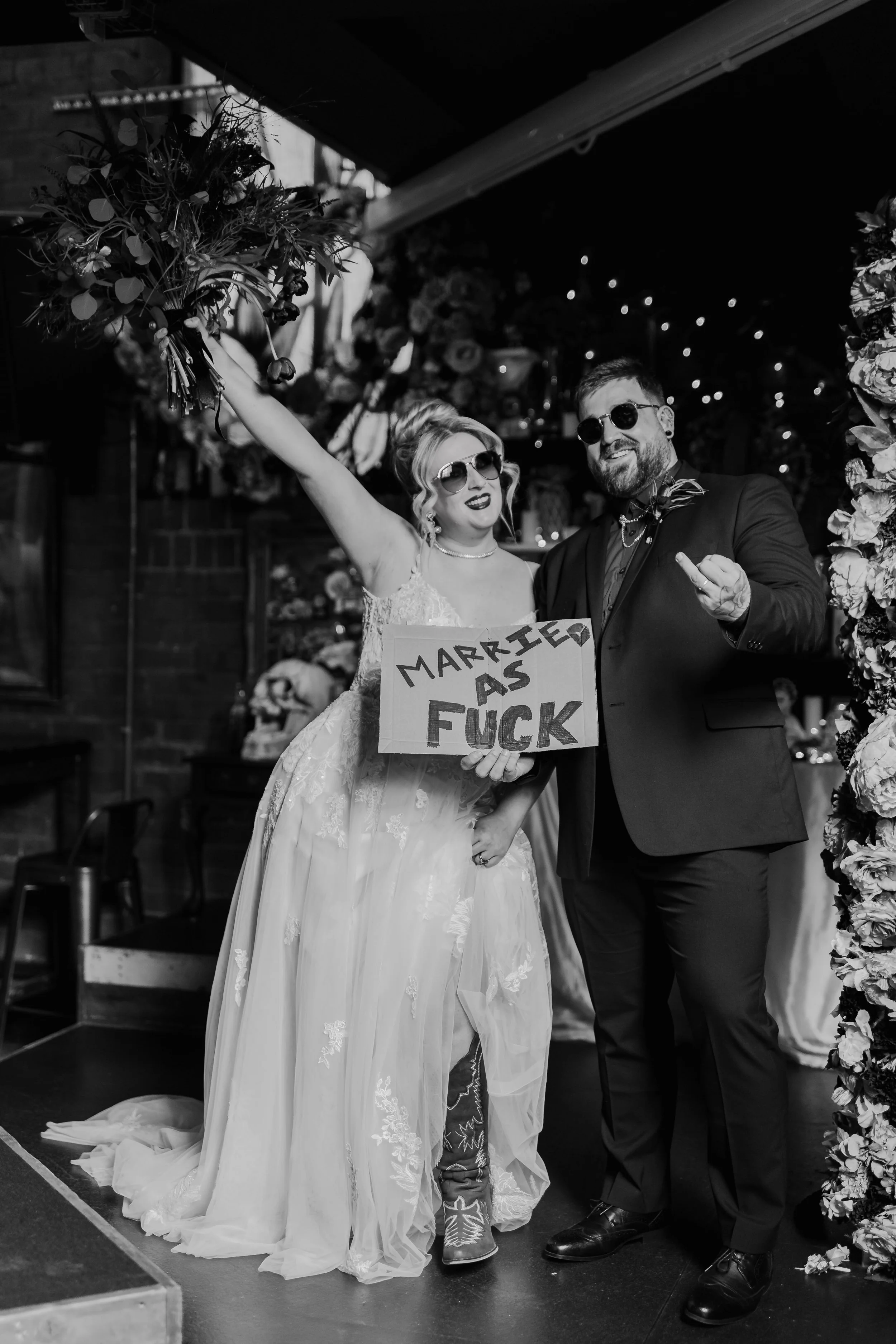 Fun alternative wedding couple with bold “married as fuck” sign at Church Temple of Fun wedding venue Sheffield