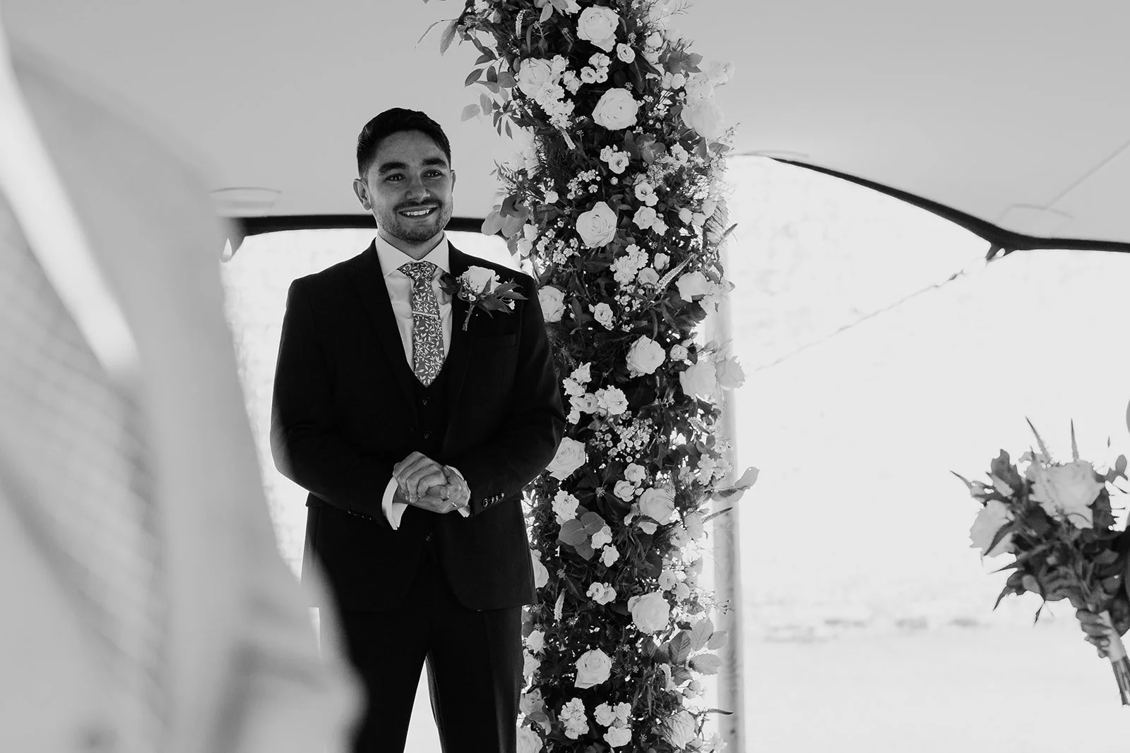 Rory waiting beneath the floral ceremony arch at Scrivelsby Walled Garden