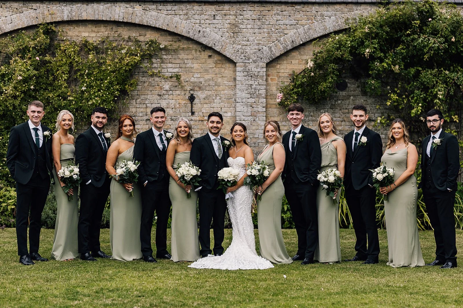 Charlotte and Rory with their wedding party beside the brick garden wall