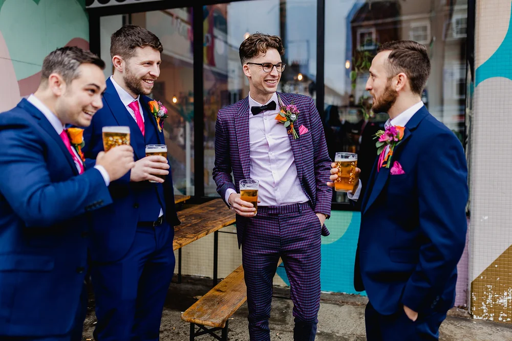 Callum laughing with friends and sharing a drink on his wedding day