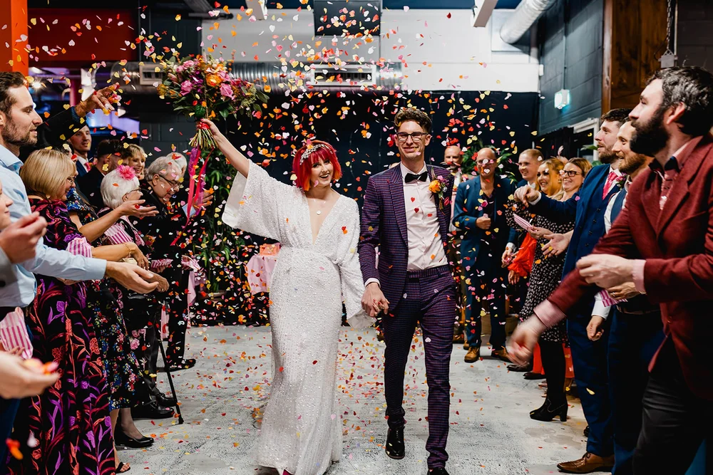 Amy and Callum celebrating in a shower of colourful confetti outside Social in Hull