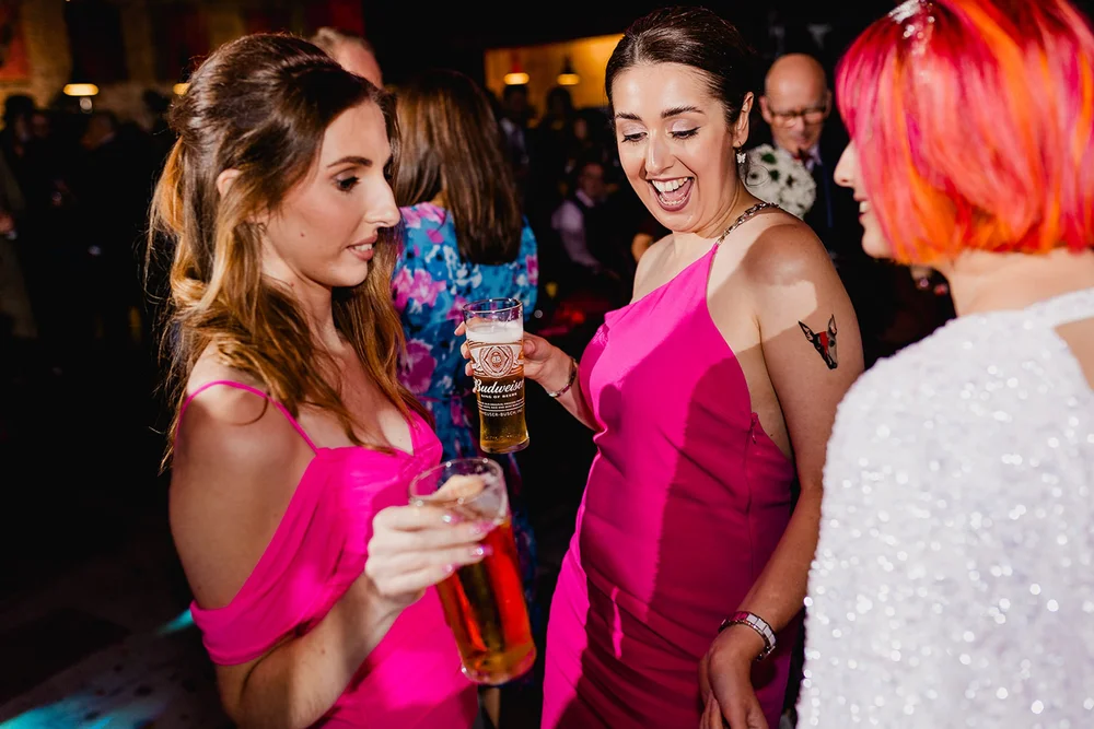 Amy laughing and dancing with bridesmaids in bright pink dresses at her evening reception