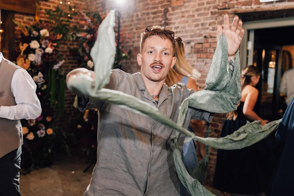 A wedding guest dancing with a flowing scarf at Ellie and Dave’s Riverlands evening party