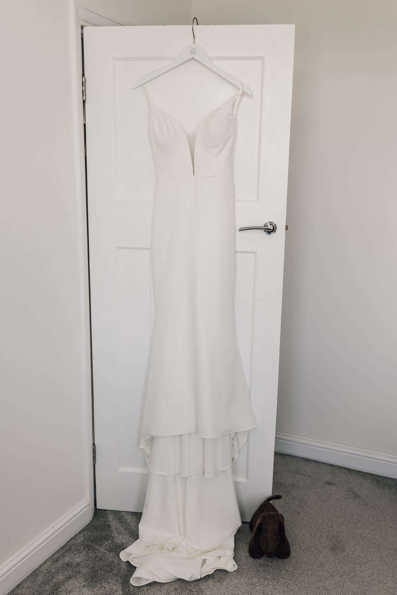 Rachel’s wedding dress hanging from a door before her wedding at The Beverley Barn