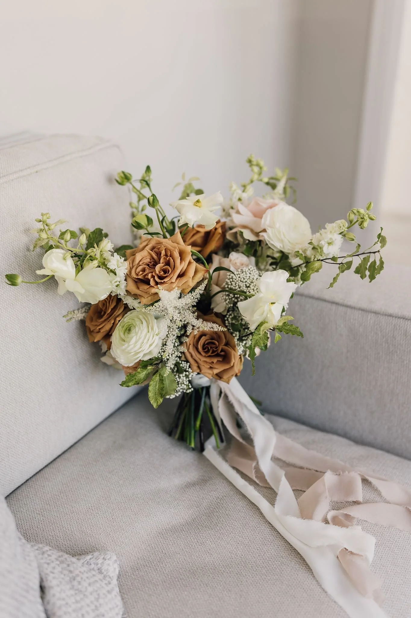 Rachel’s bouquet of white flowers and pale roses resting on a chair