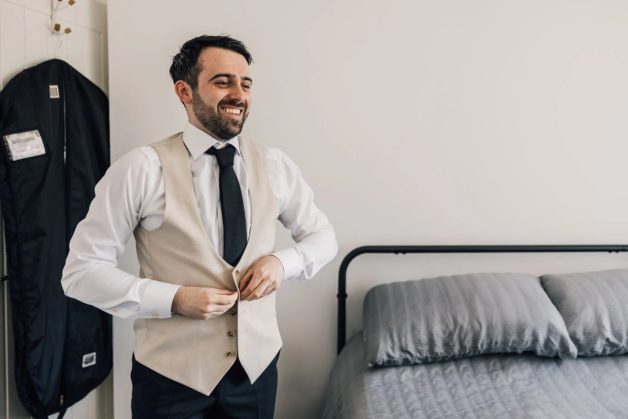 Harry fastening his waistcoat while getting ready for his wedding