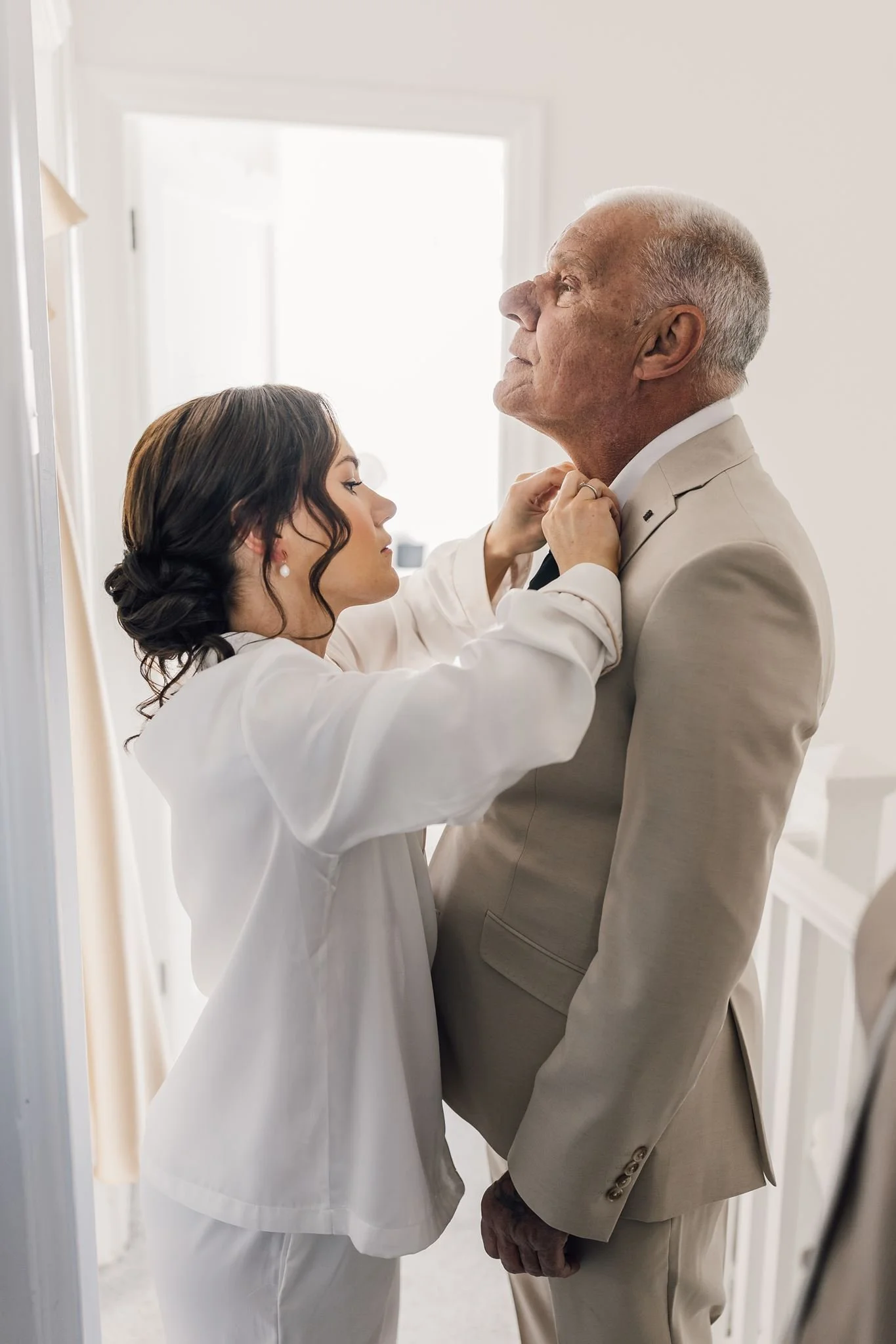 A wedding guest helping straighten a tie before the ceremony