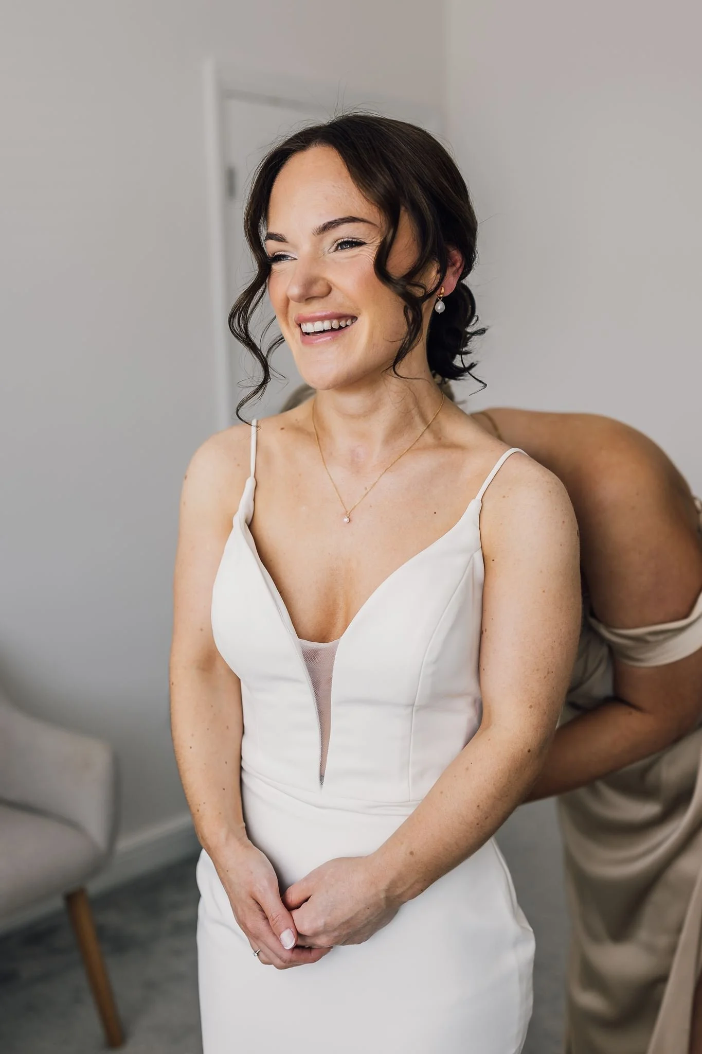 Rachel smiling as her wedding dress is fastened