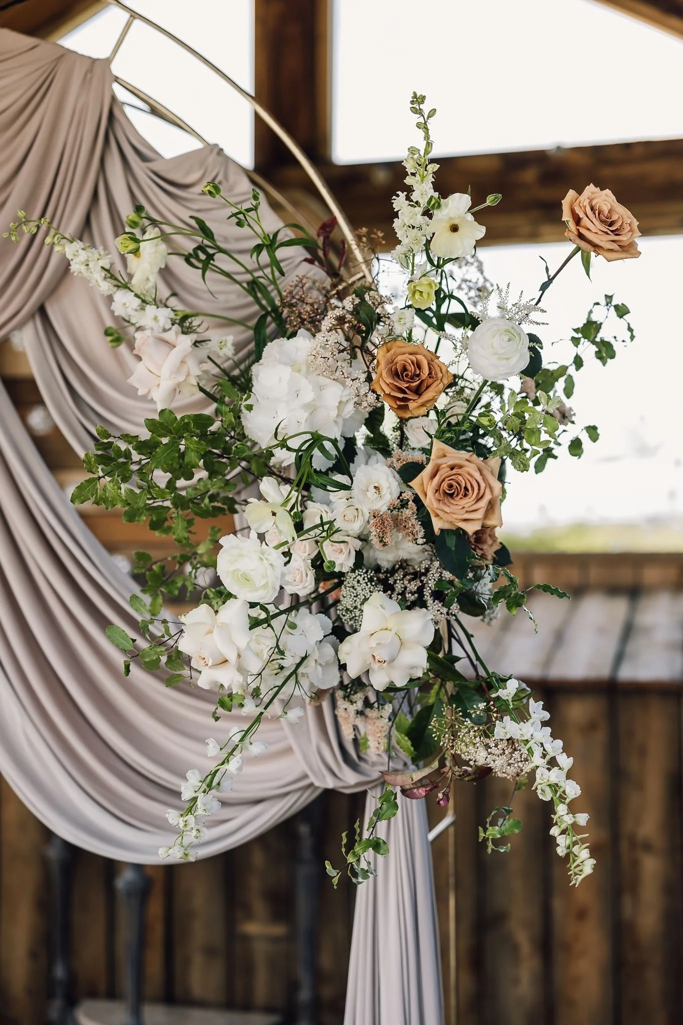 White flowers and pale roses on the outdoor ceremony backdrop