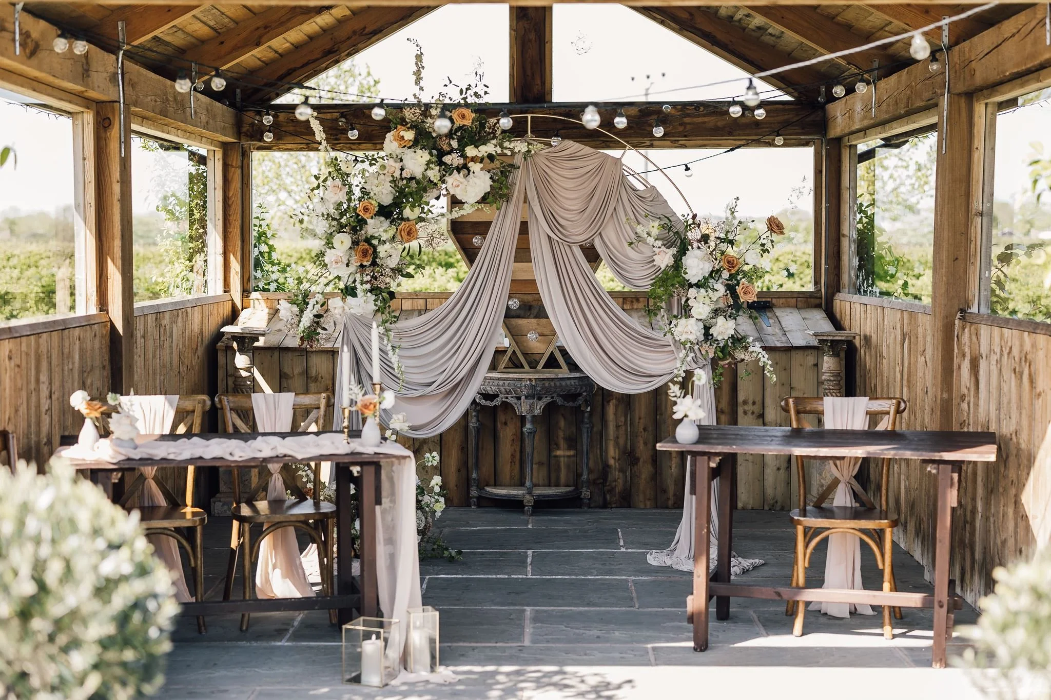 Flowers and draping decorating the outdoor ceremony shelter at The Beverley Barn