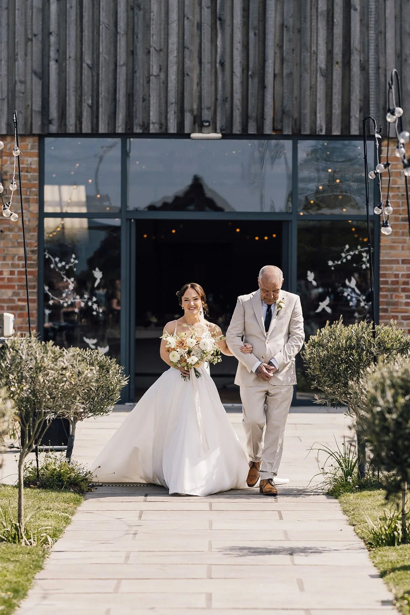 Rachel and her dad walking out of The Beverley Barn towards the ceremony