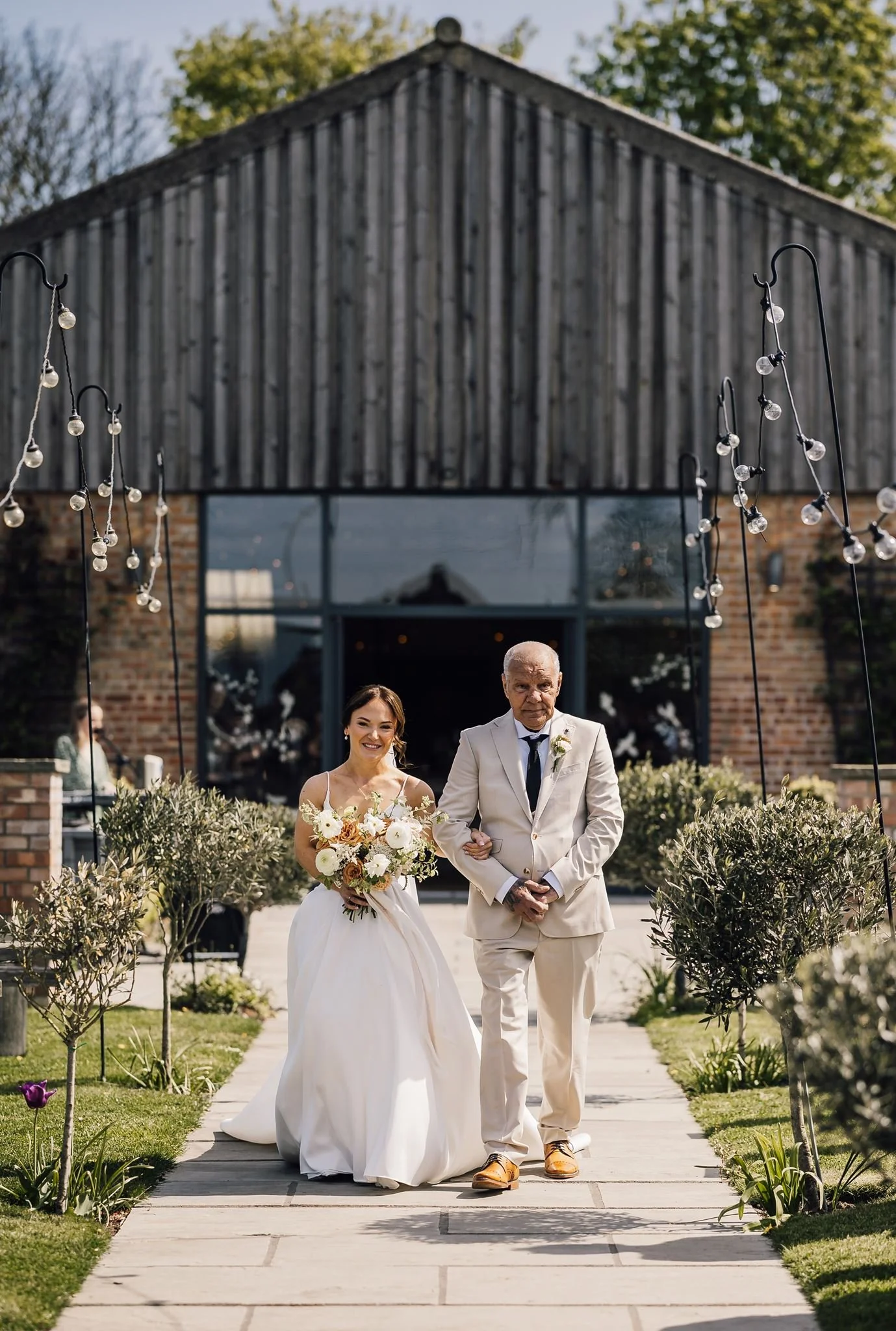 Rachel and her dad approaching the outdoor ceremony along the garden path