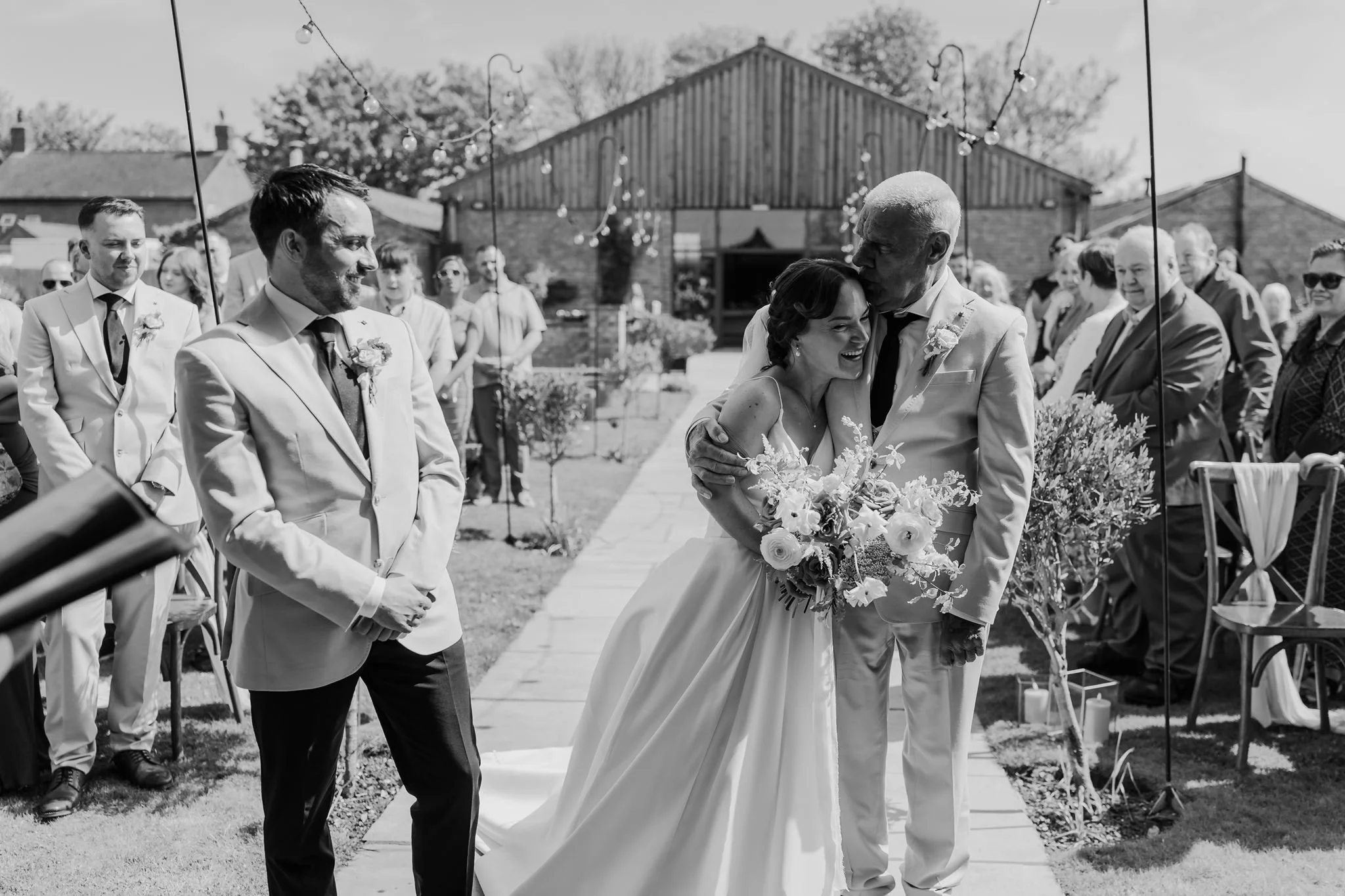 Rachel and her dad walking up the wedding aisle, in black and white