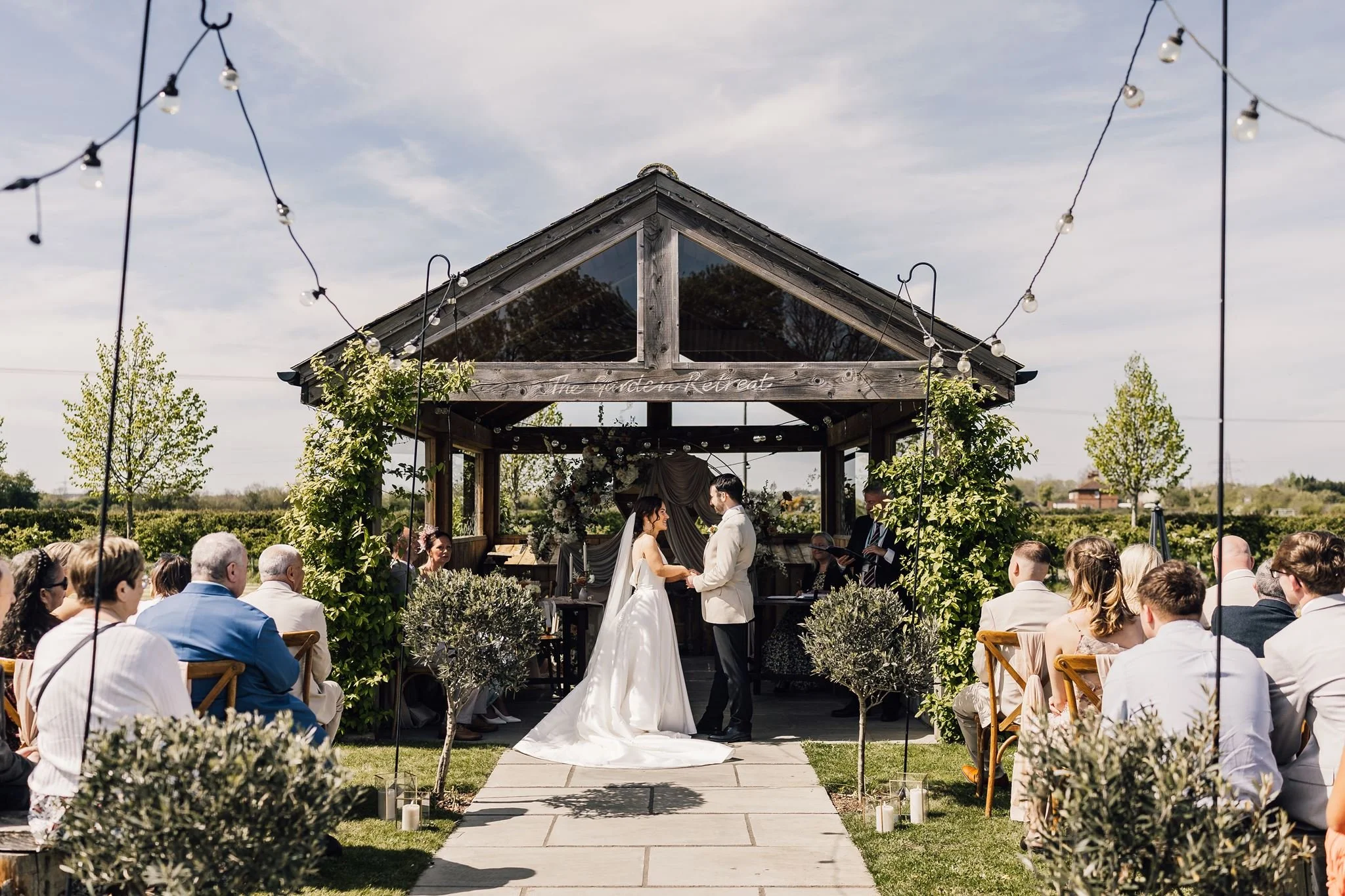 Guests watching Rachel and Harry’s ceremony beneath the garden shelter