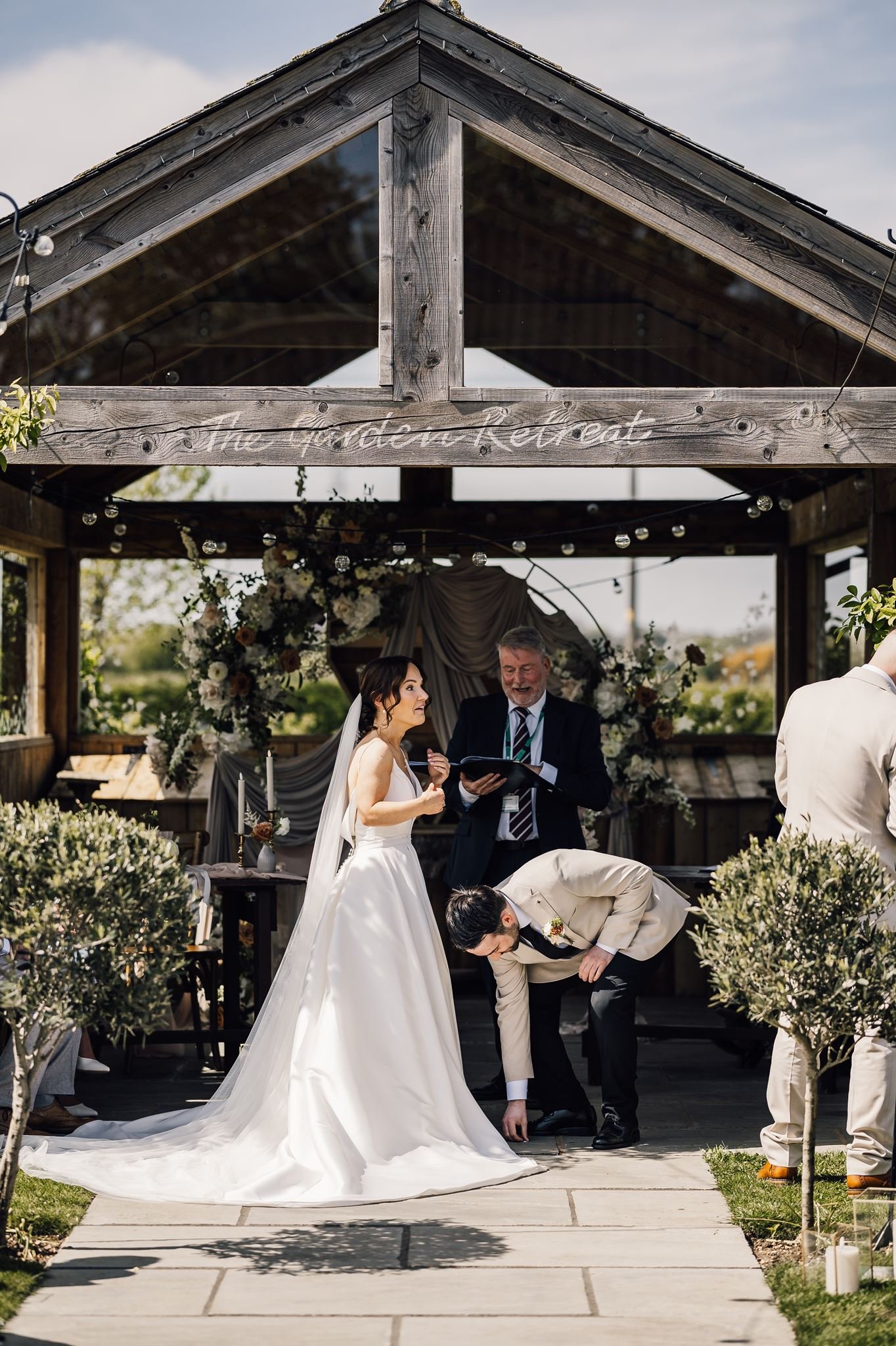 Rachel and Harry exchanging vows beneath the flower-decorated ceremony shelter