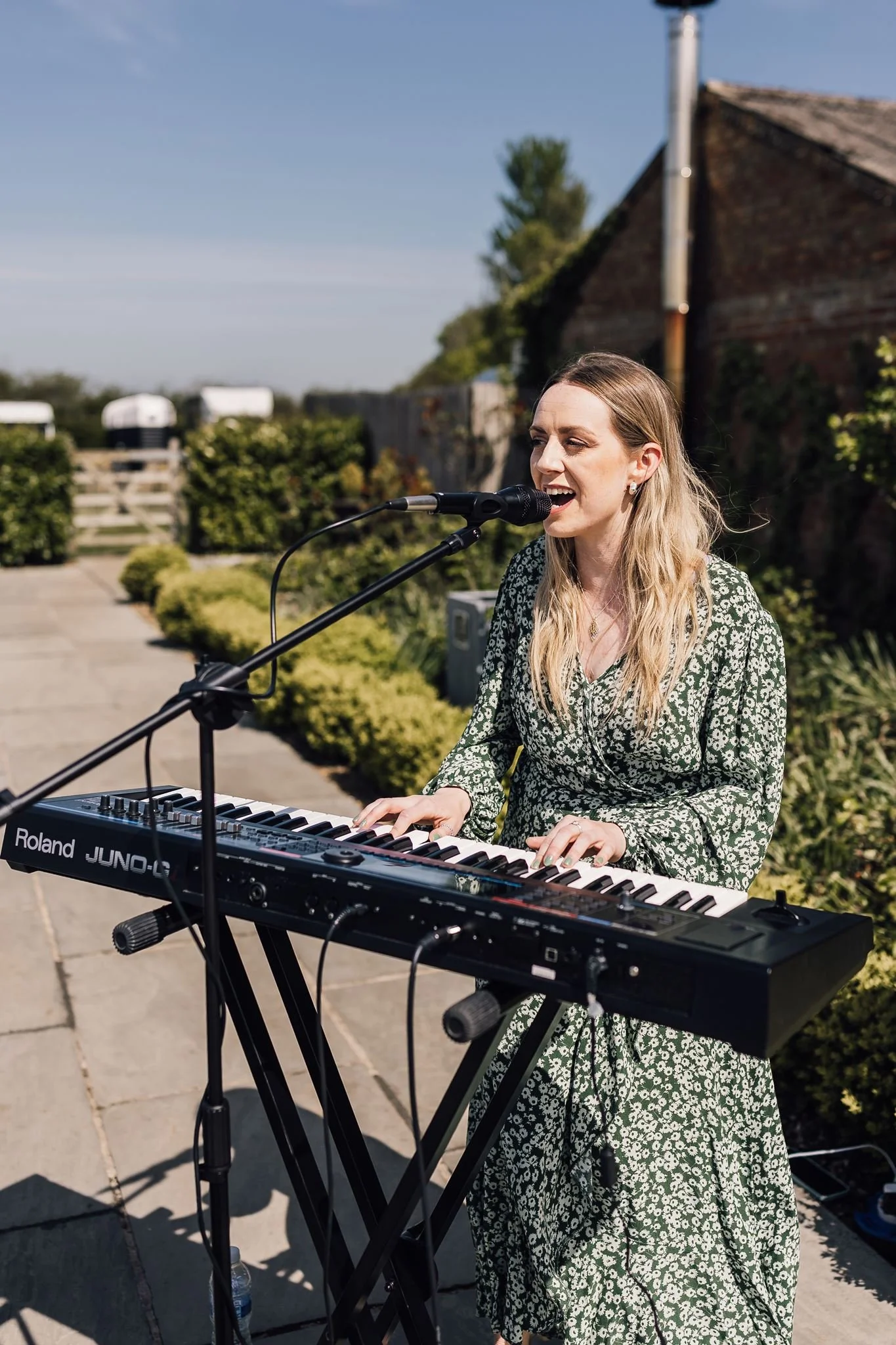 A singer performing at a keyboard beside the outdoor ceremony