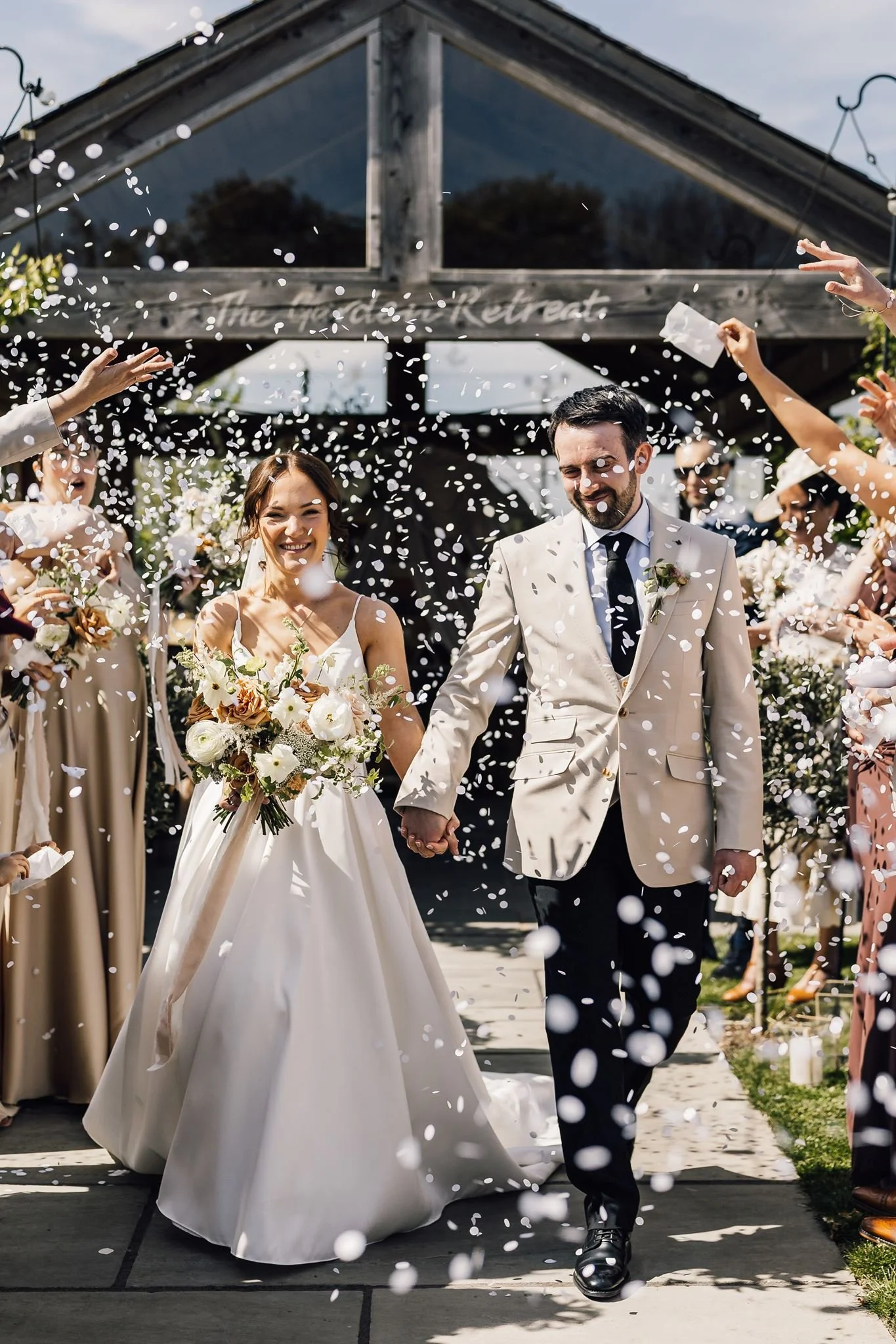 Rachel and Harry walking through confetti after their outdoor ceremony
