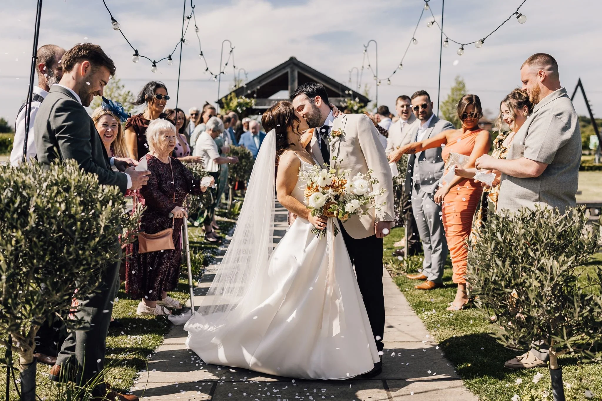 Guests throwing confetti as Rachel and Harry walk down the garden aisle