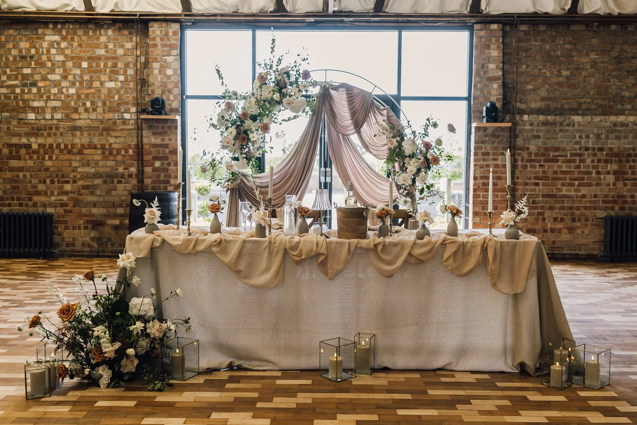 The wedding top table decorated with pale flowers and draping