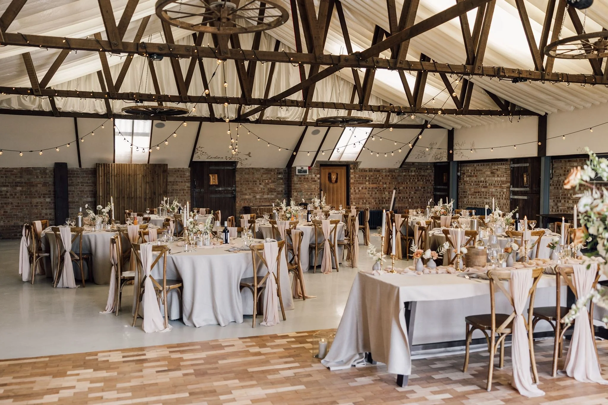 Wedding breakfast tables beneath the timber beams at The Beverley Barn