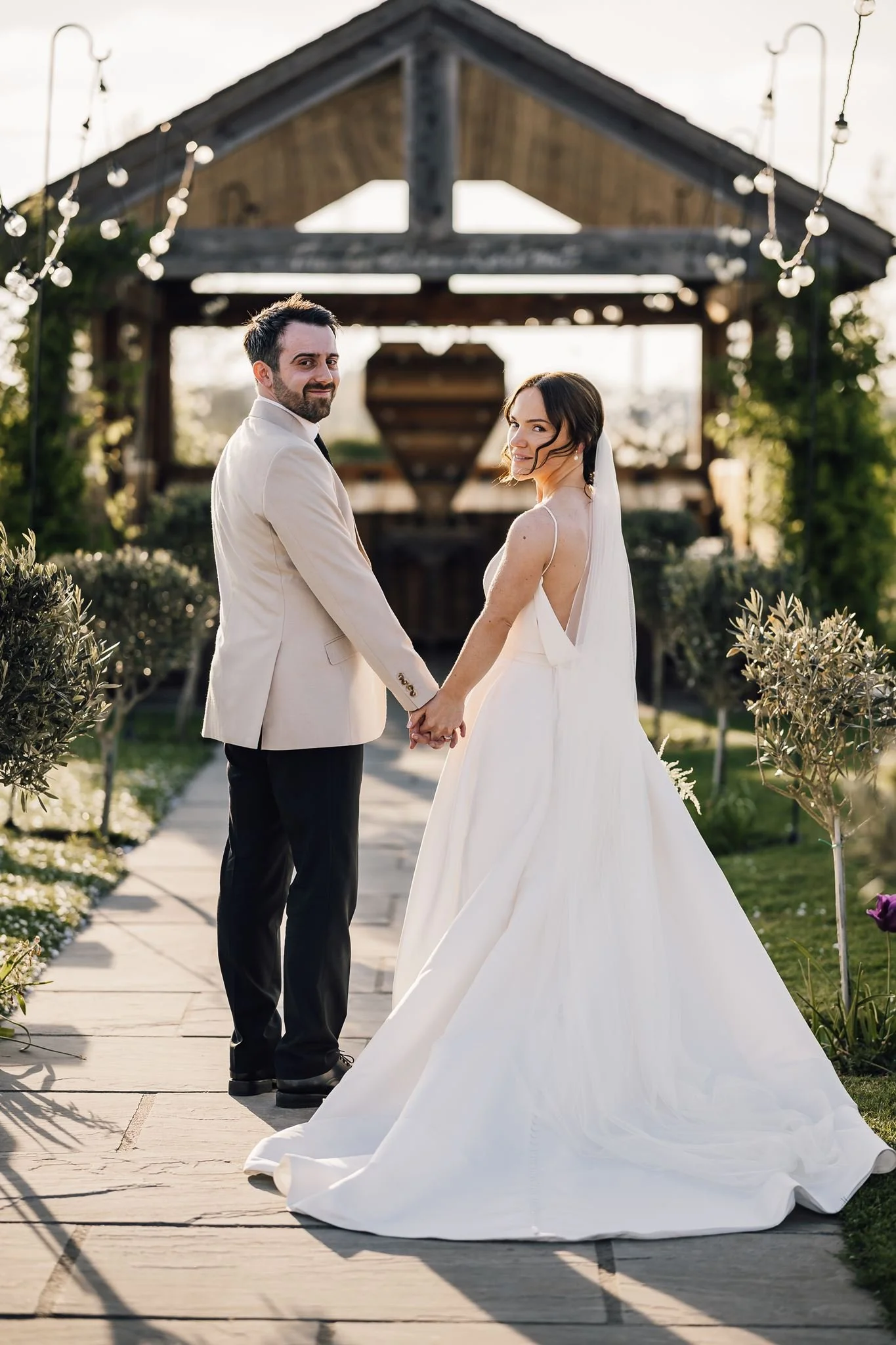 Rachel and Harry raising their joined hands beneath the garden pergola