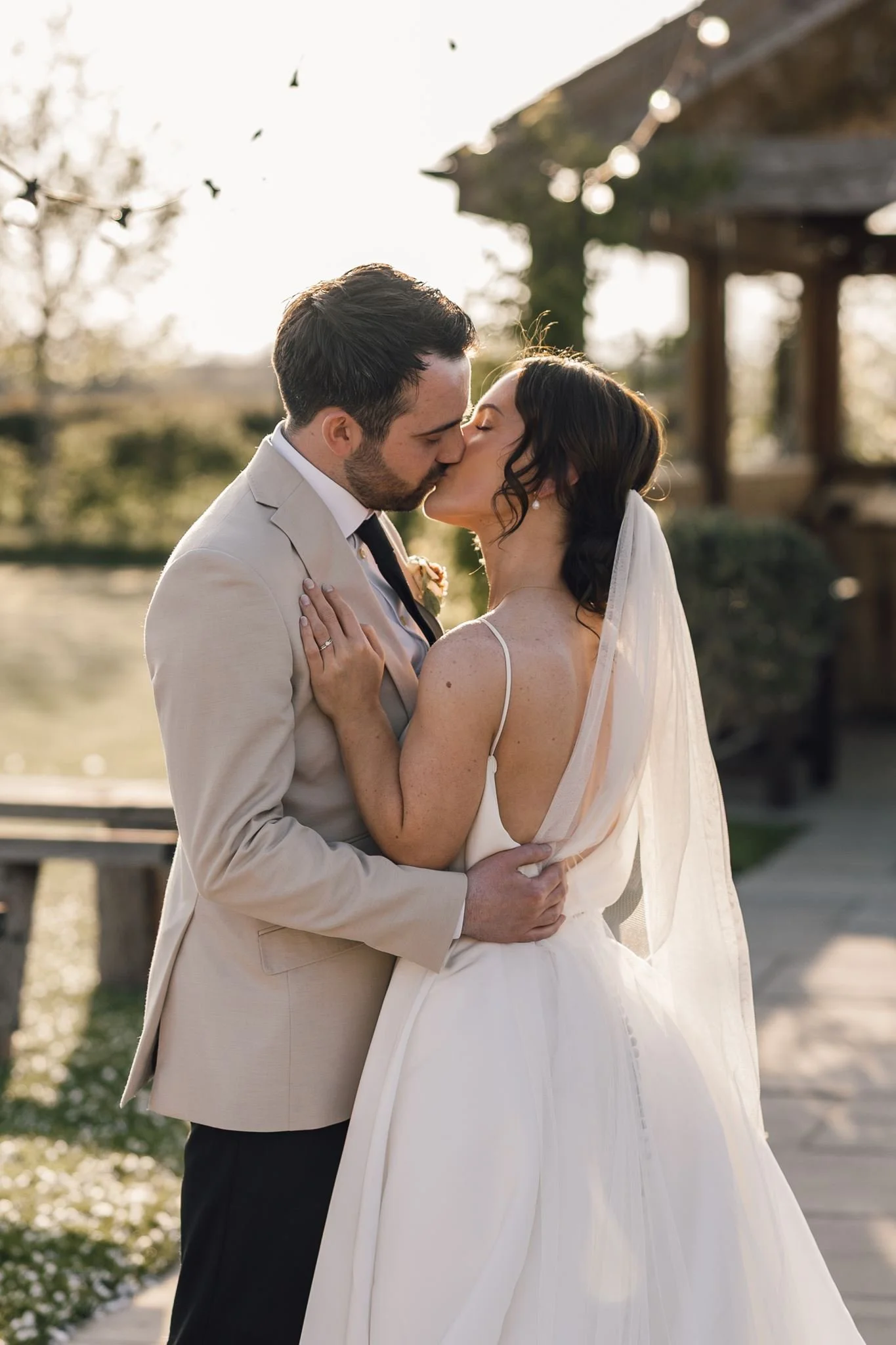 Rachel and Harry kissing in the evening light beside the ceremony shelter