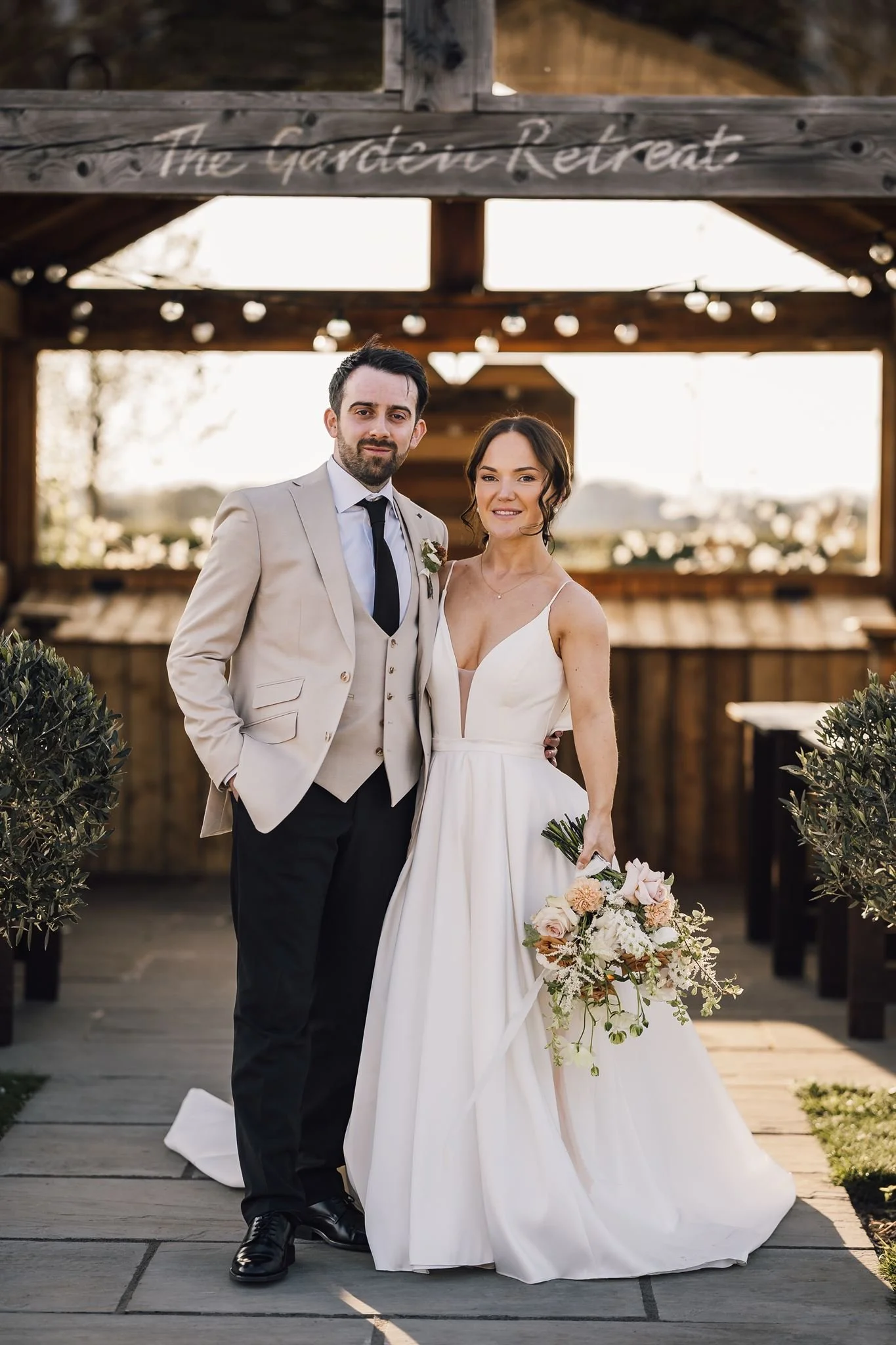 Rachel and Harry standing together beneath the timber ceremony shelter
