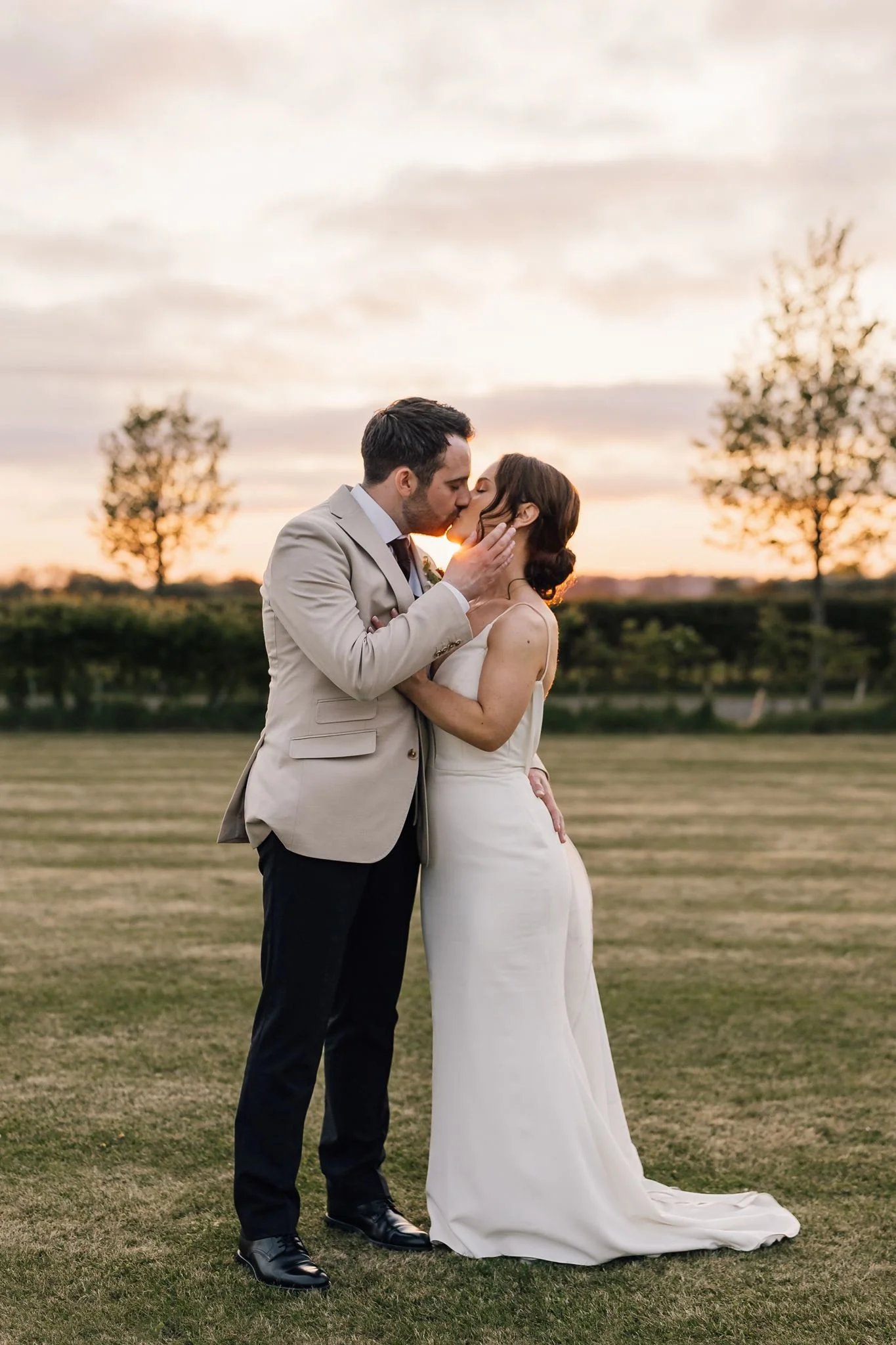 Rachel and Harry kissing on the lawn in the soft evening light