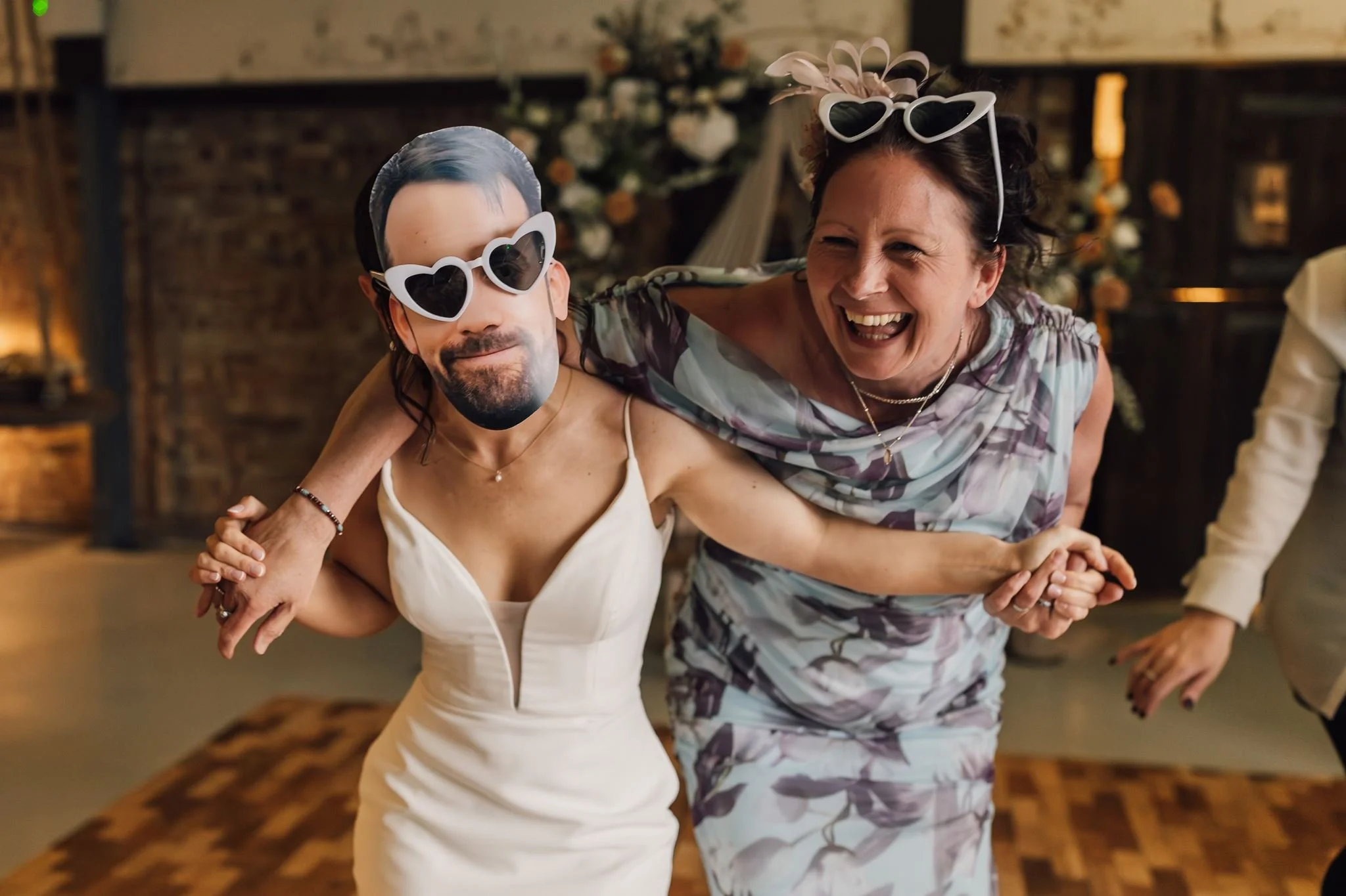 Two guests laughing and dancing in novelty sunglasses