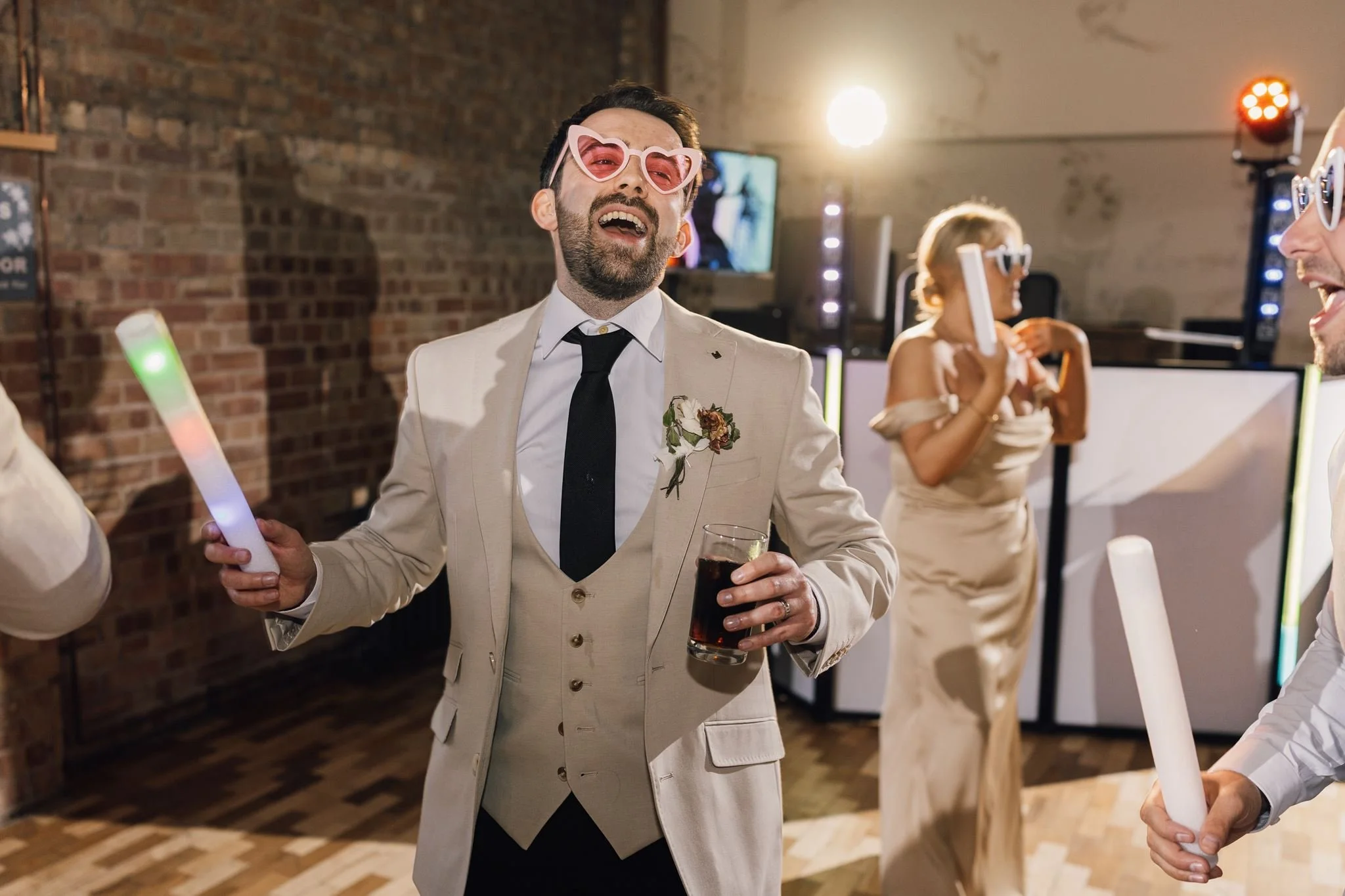 A wedding guest celebrating on the dance floor with a light-up foam stick