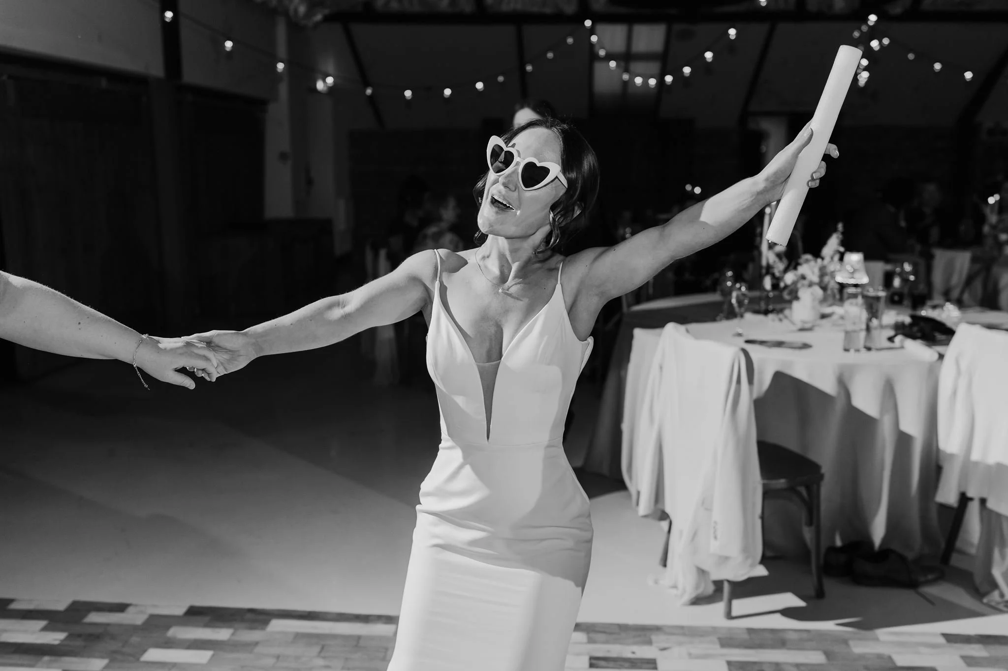 A guest throwing their arms wide on the dance floor, in black and white
