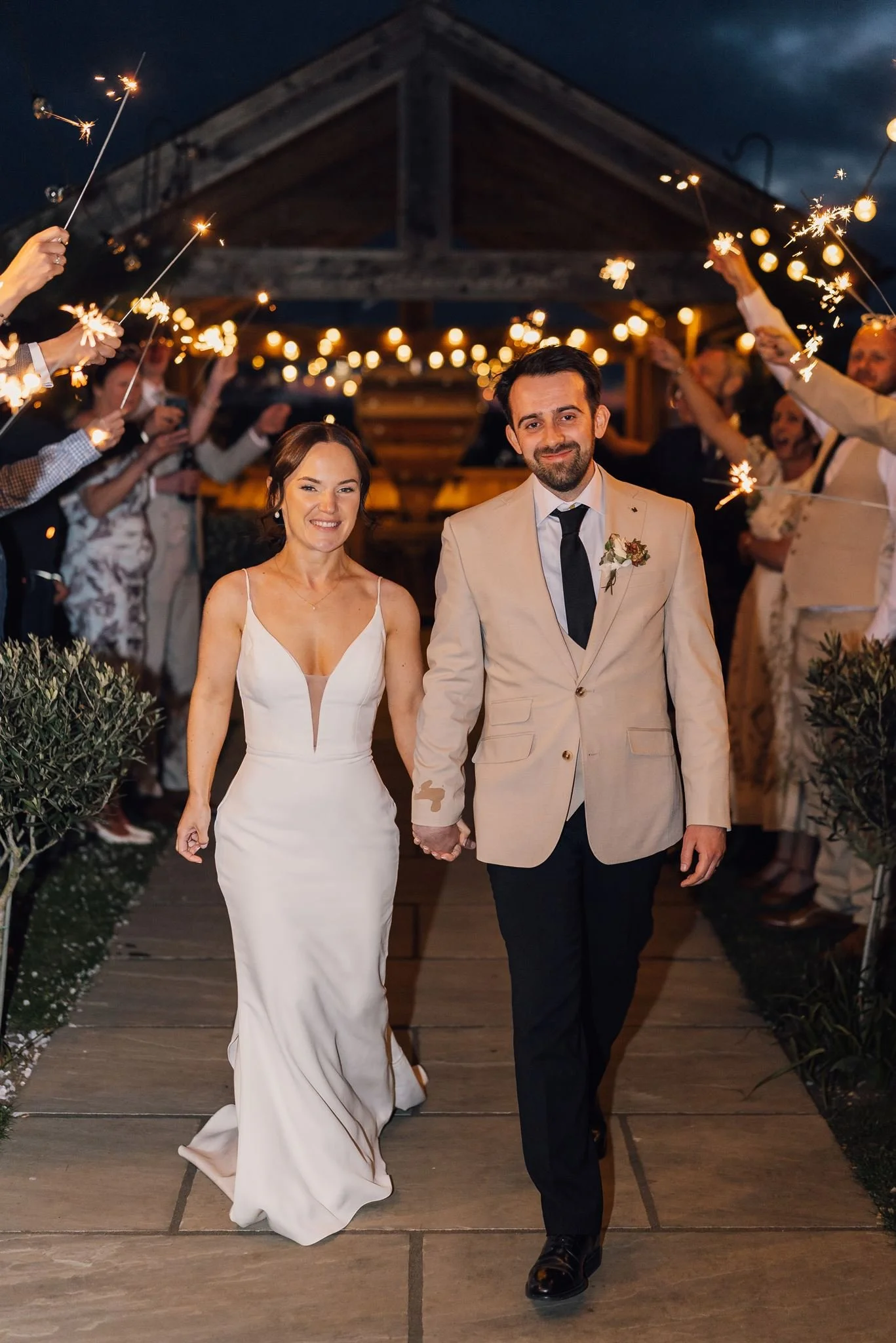 Rachel and Harry walking beneath sparklers outside The Beverley Barn