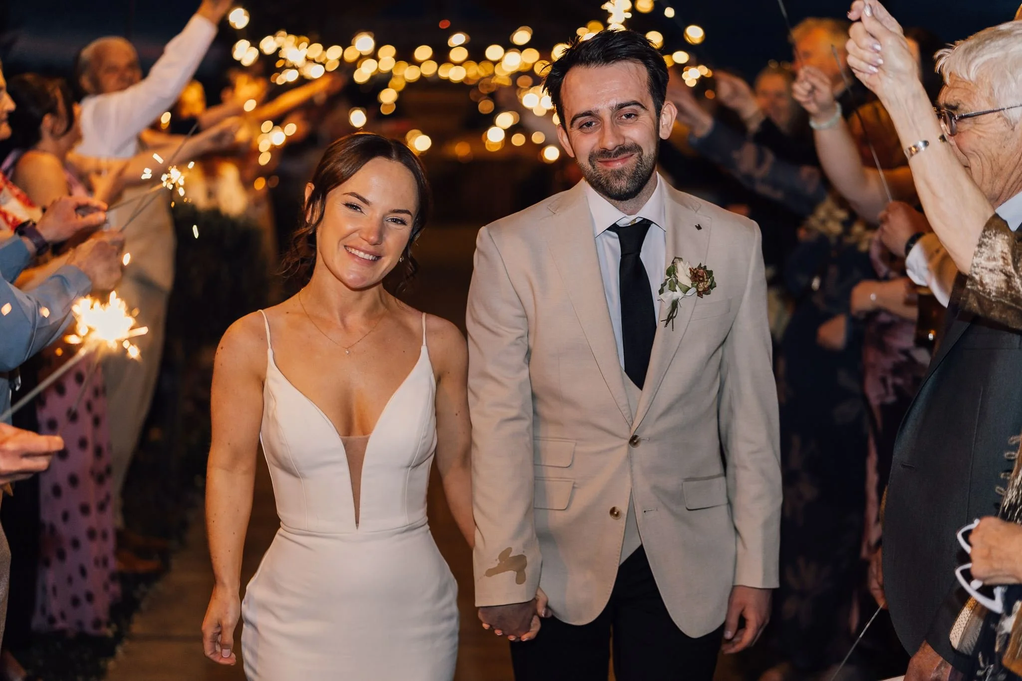 Rachel and Harry laughing as they walk through a sparkler tunnel
