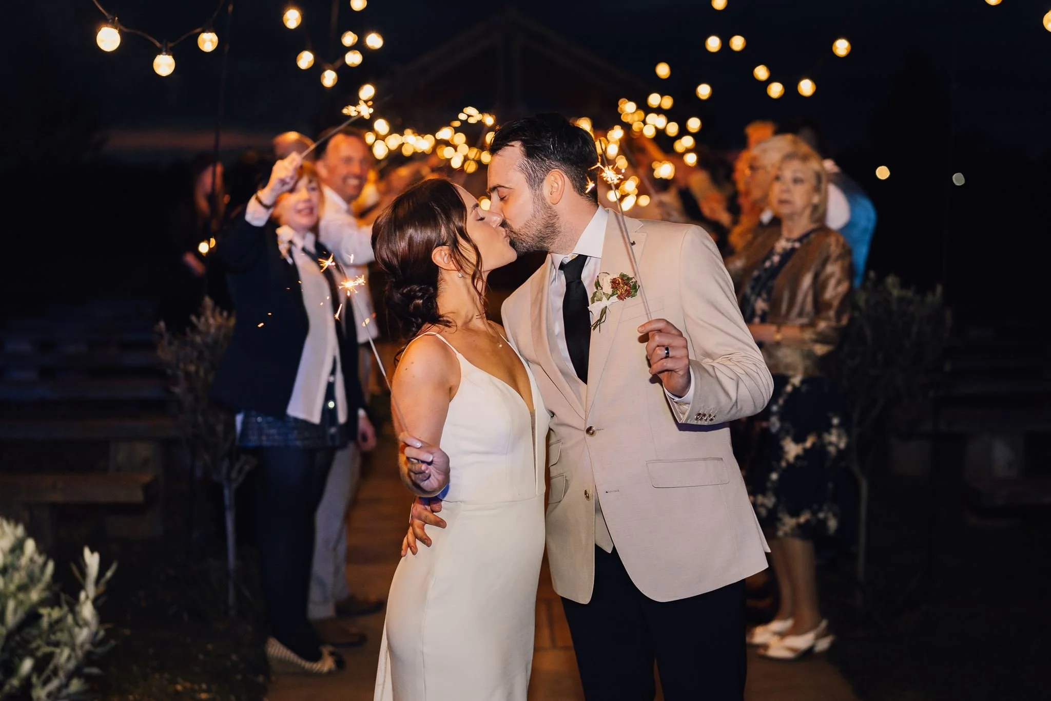 Rachel and Harry kissing beneath the wedding sparklers