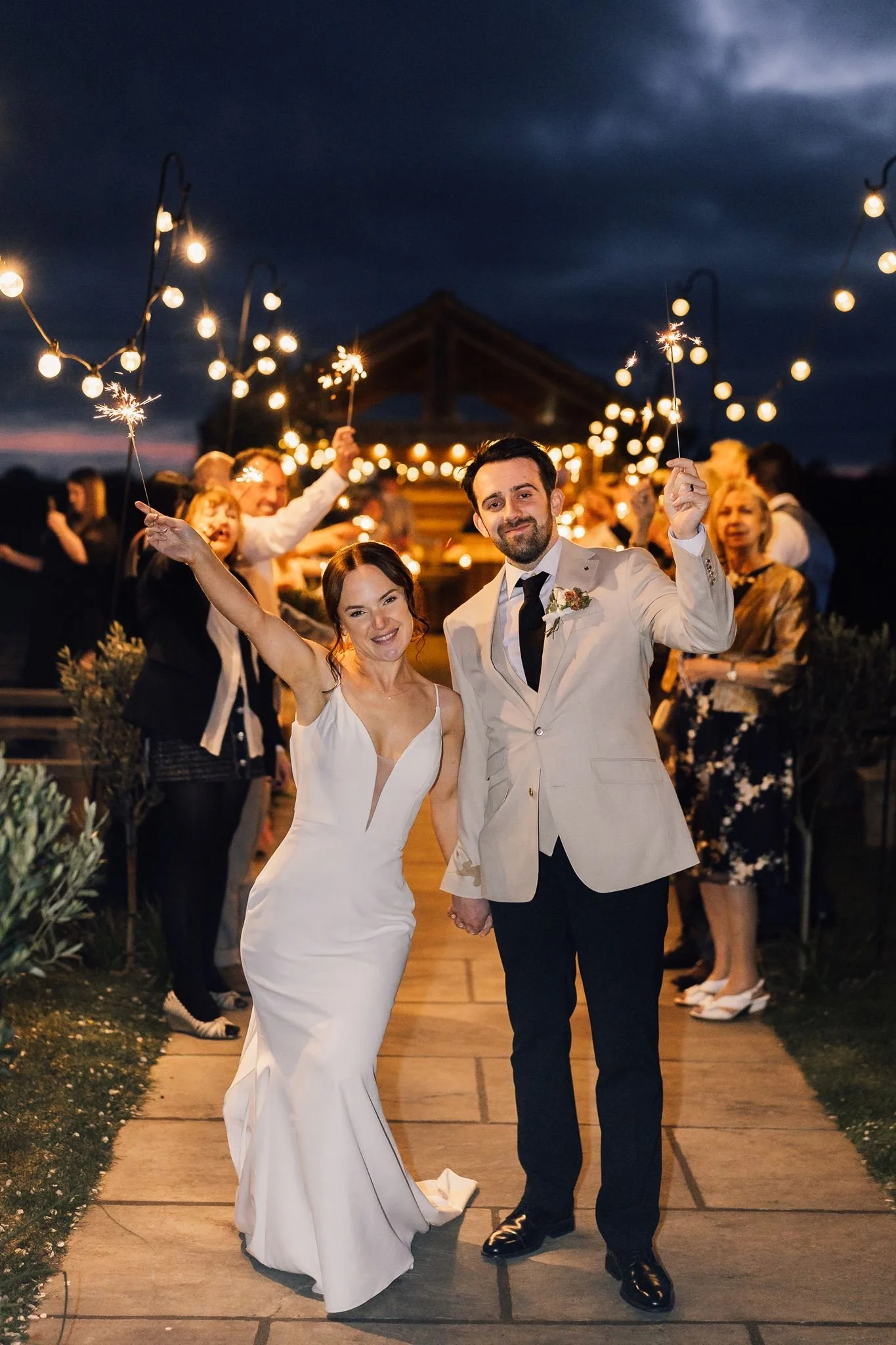 Rachel and Harry walking towards the camera through a sparkler tunnel