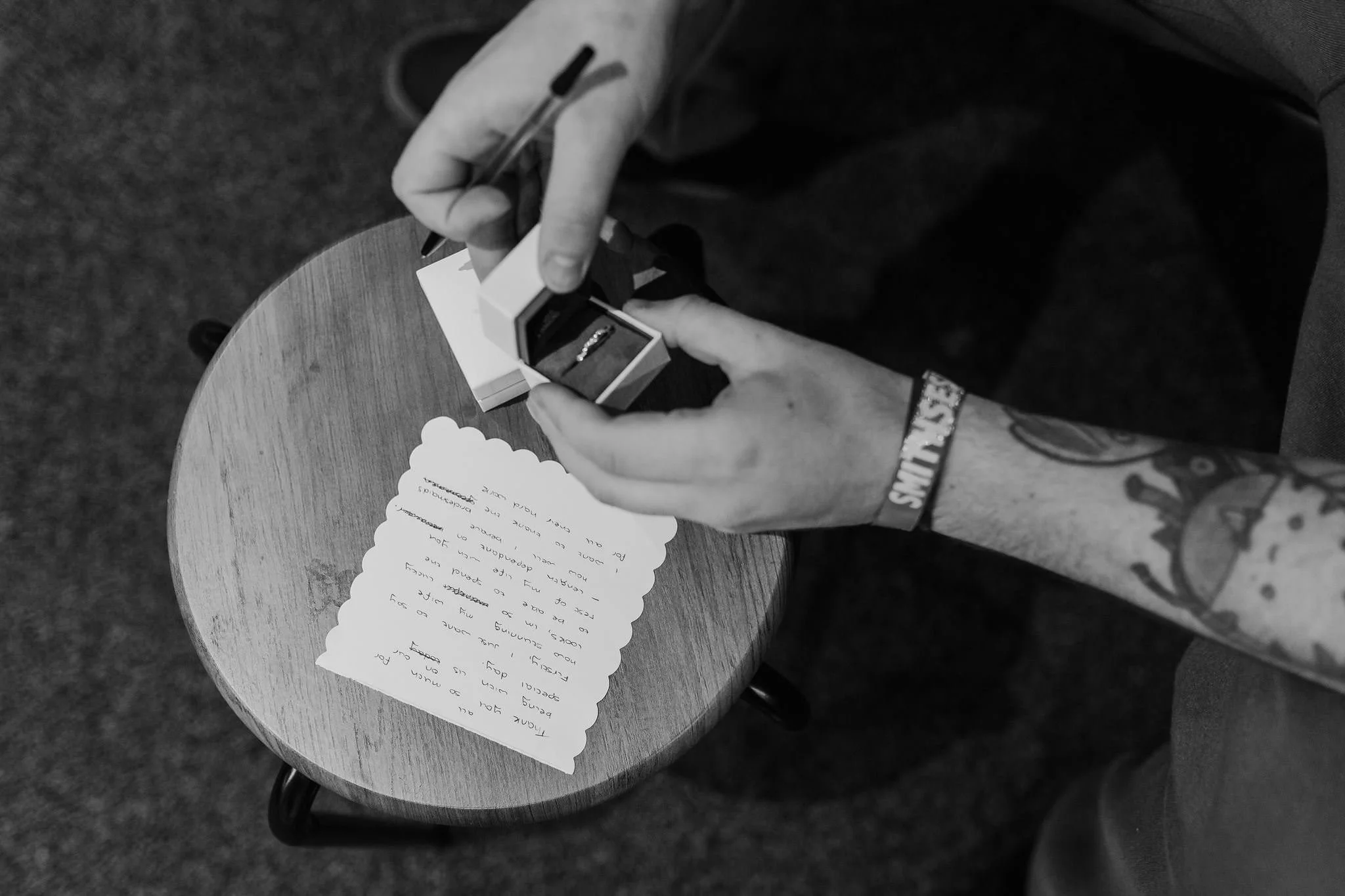 Black and white photograph of wedding vows being written in a notebook