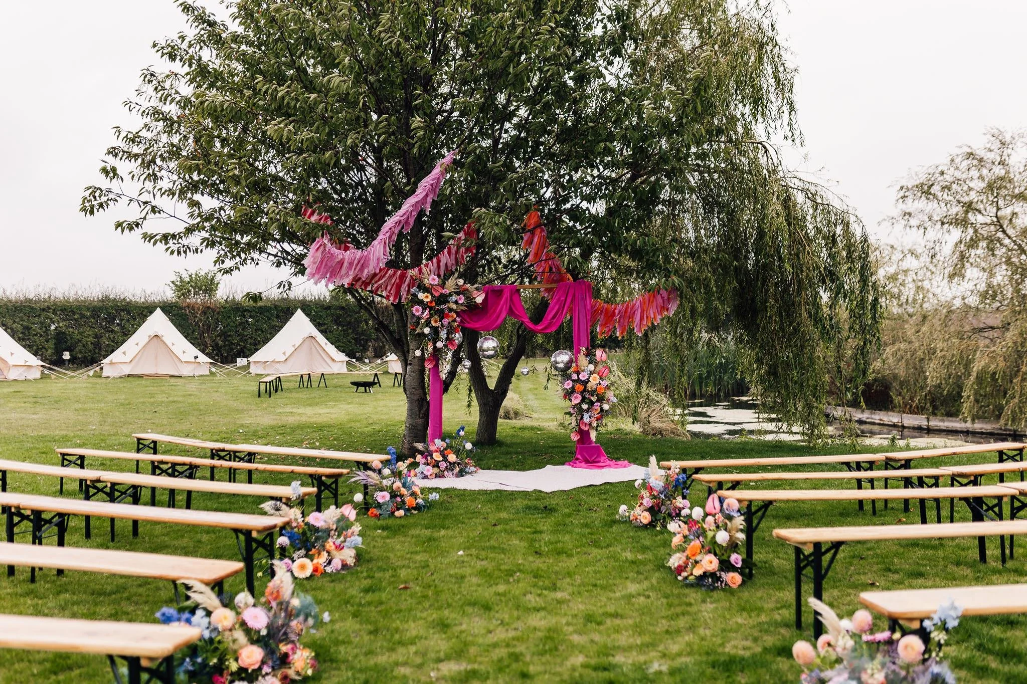 Outdoor ceremony benches and a pink floral arch at Pitch 21 in East Yorkshire