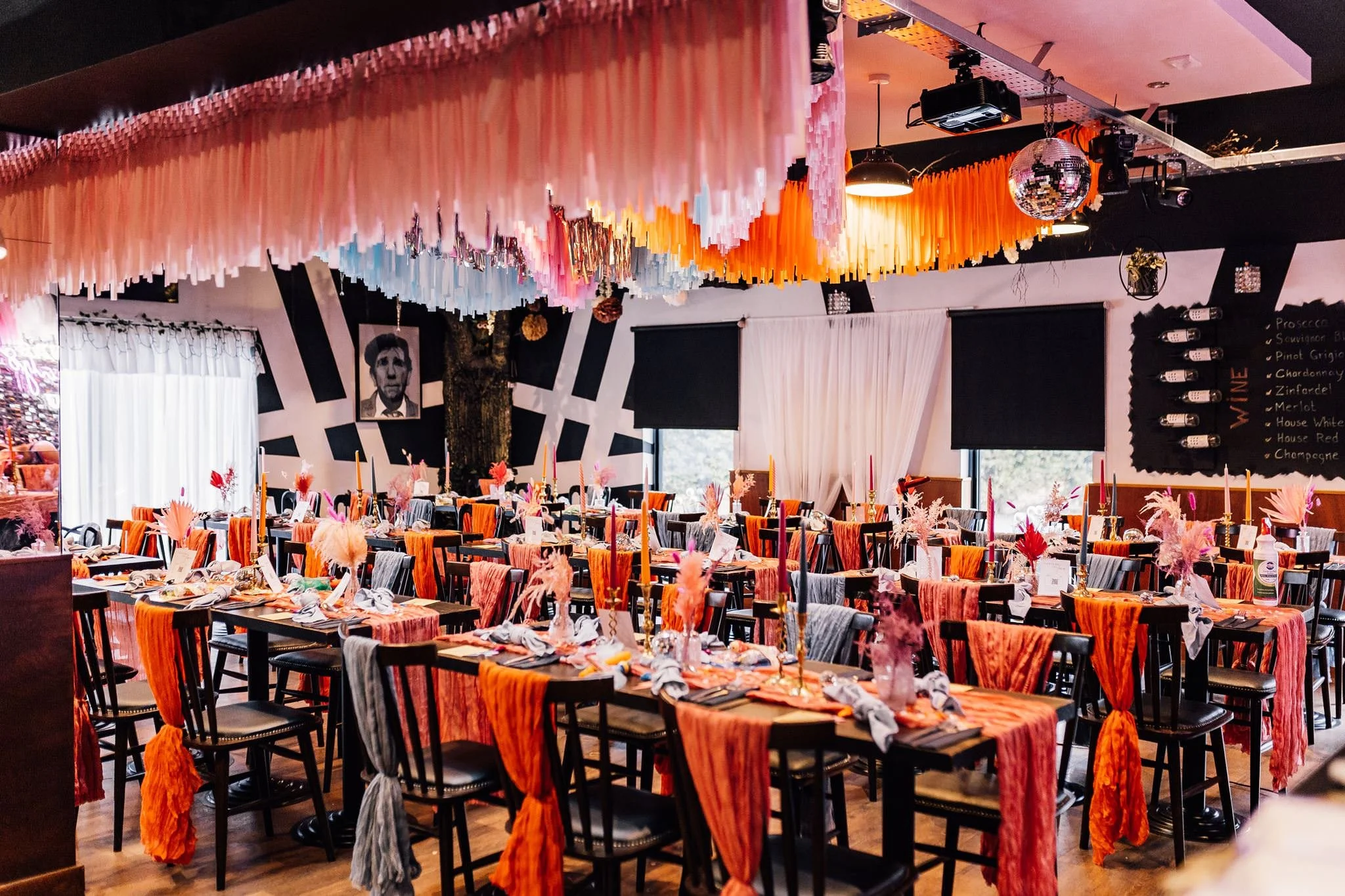 Festival wedding reception tables beneath colourful ceiling streamers at Pitch 21