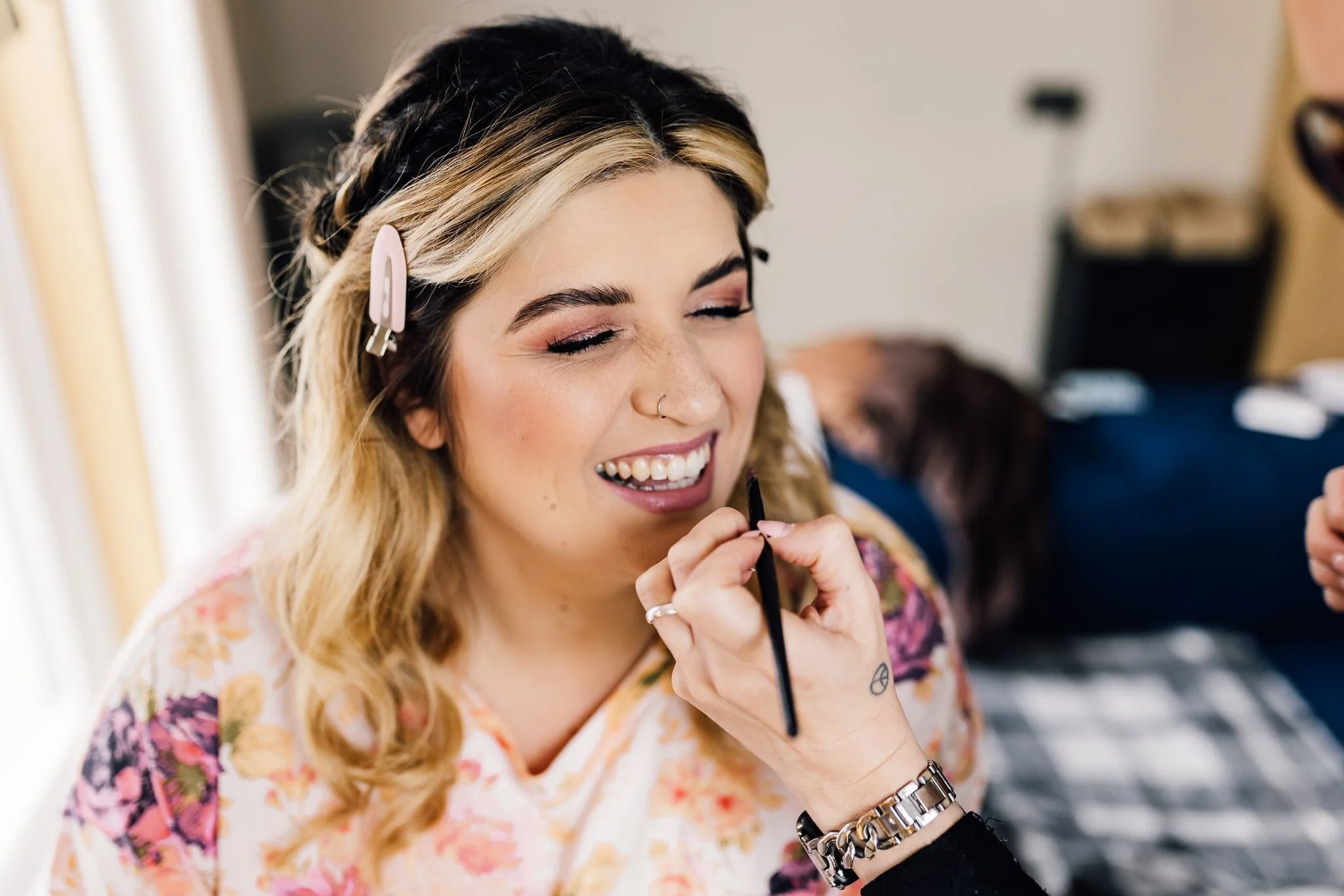 Chloe smiling while her wedding makeup is applied