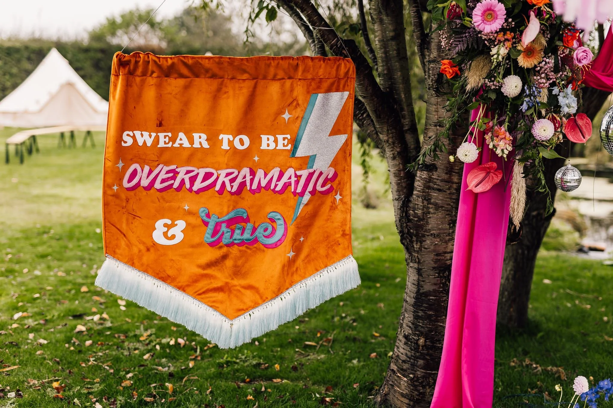 Orange lyric banner beside Chloe and Aaron’s outdoor ceremony