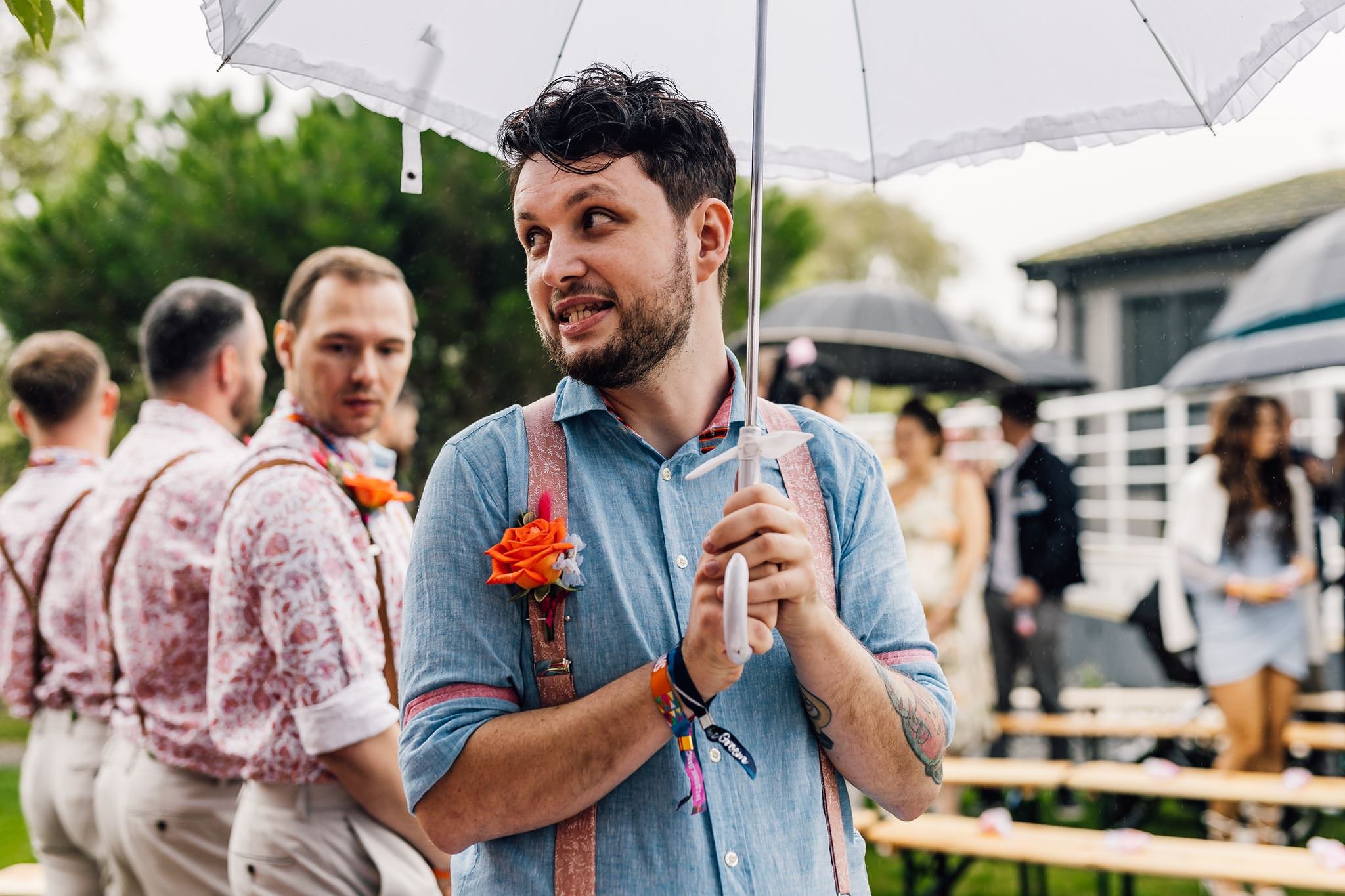 Aaron smiling beneath a clear umbrella during the rainy ceremony