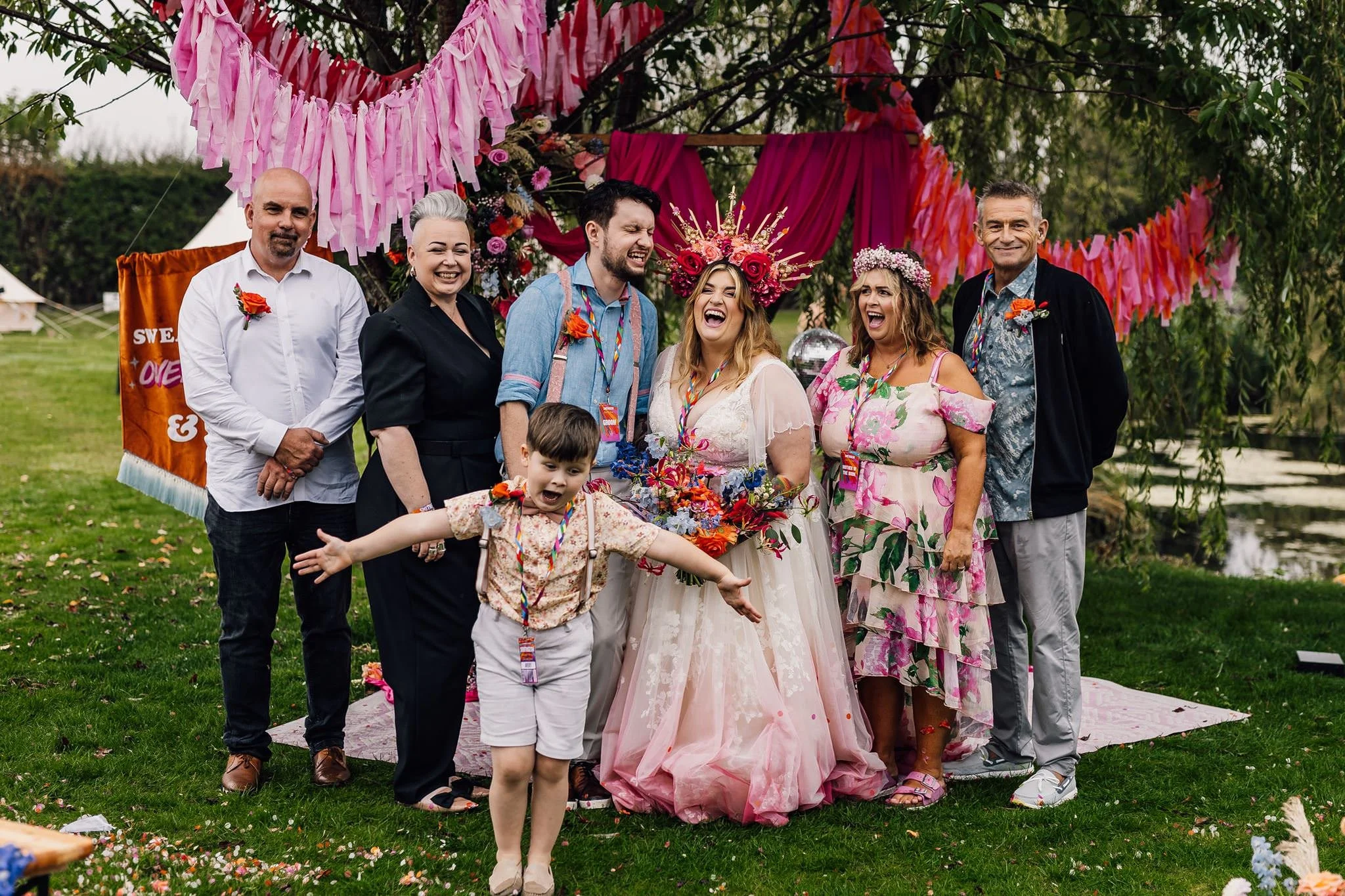A family group with Chloe and Aaron in front of the colourful ceremony backdrop