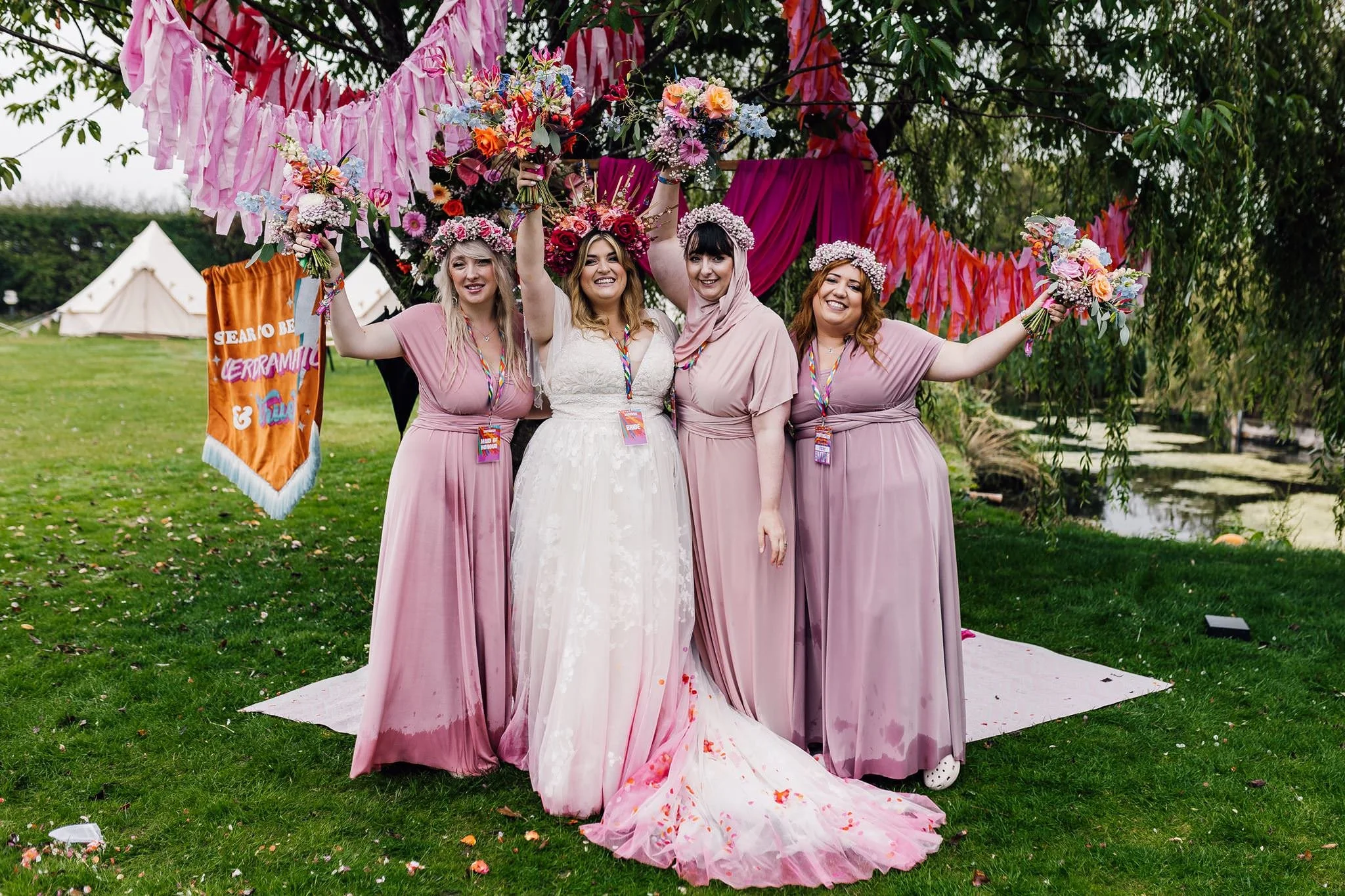 Chloe and her bridesmaids raising their arms beneath colourful ribbons