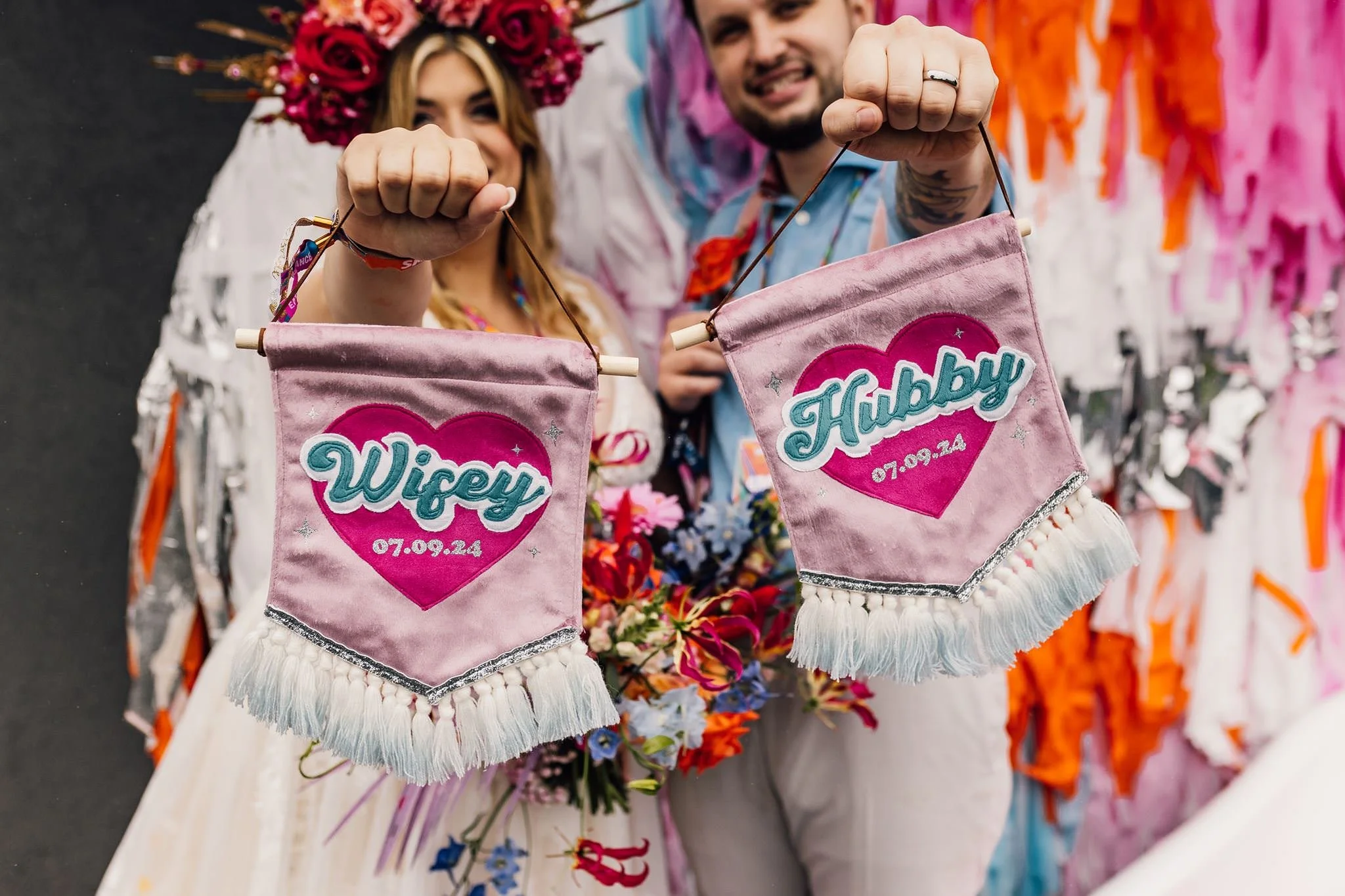 Chloe and Aaron sitting together holding personalised wedding banners