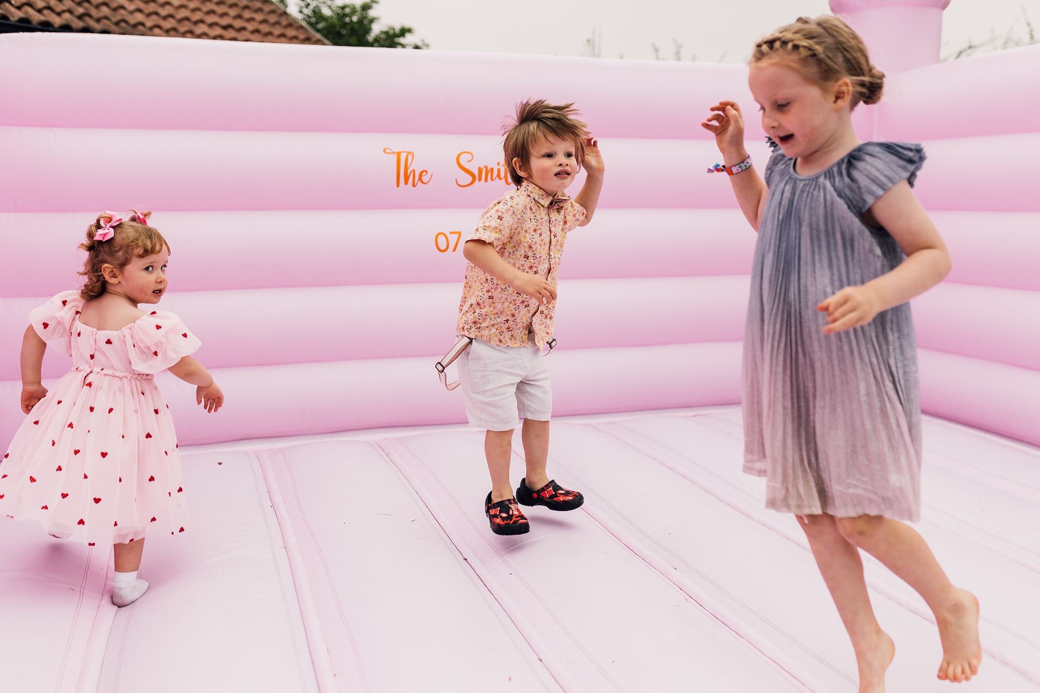 Young wedding guests jumping on a pink bouncy castle