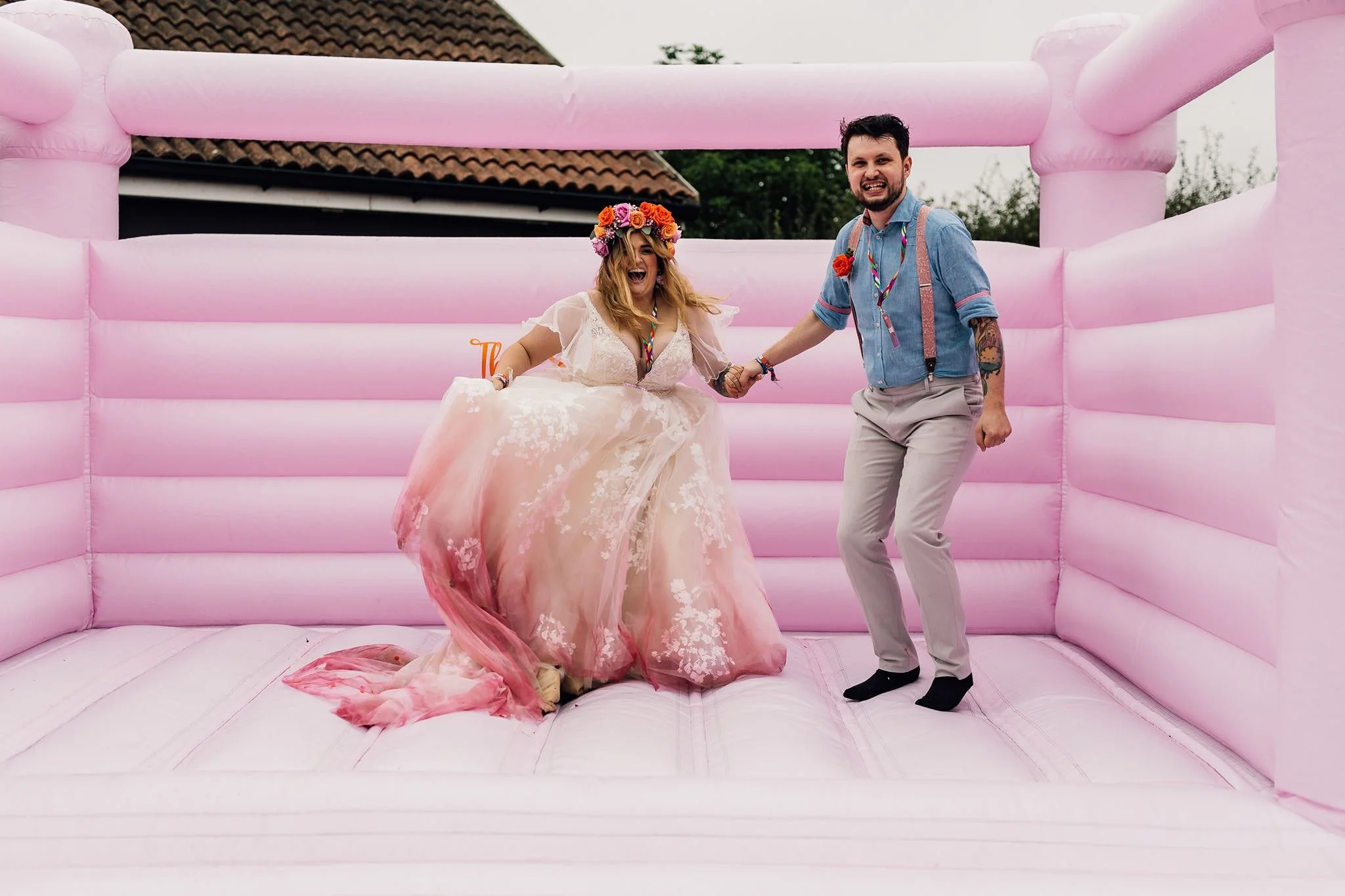 Chloe and Aaron jumping together on their pink wedding bouncy castle