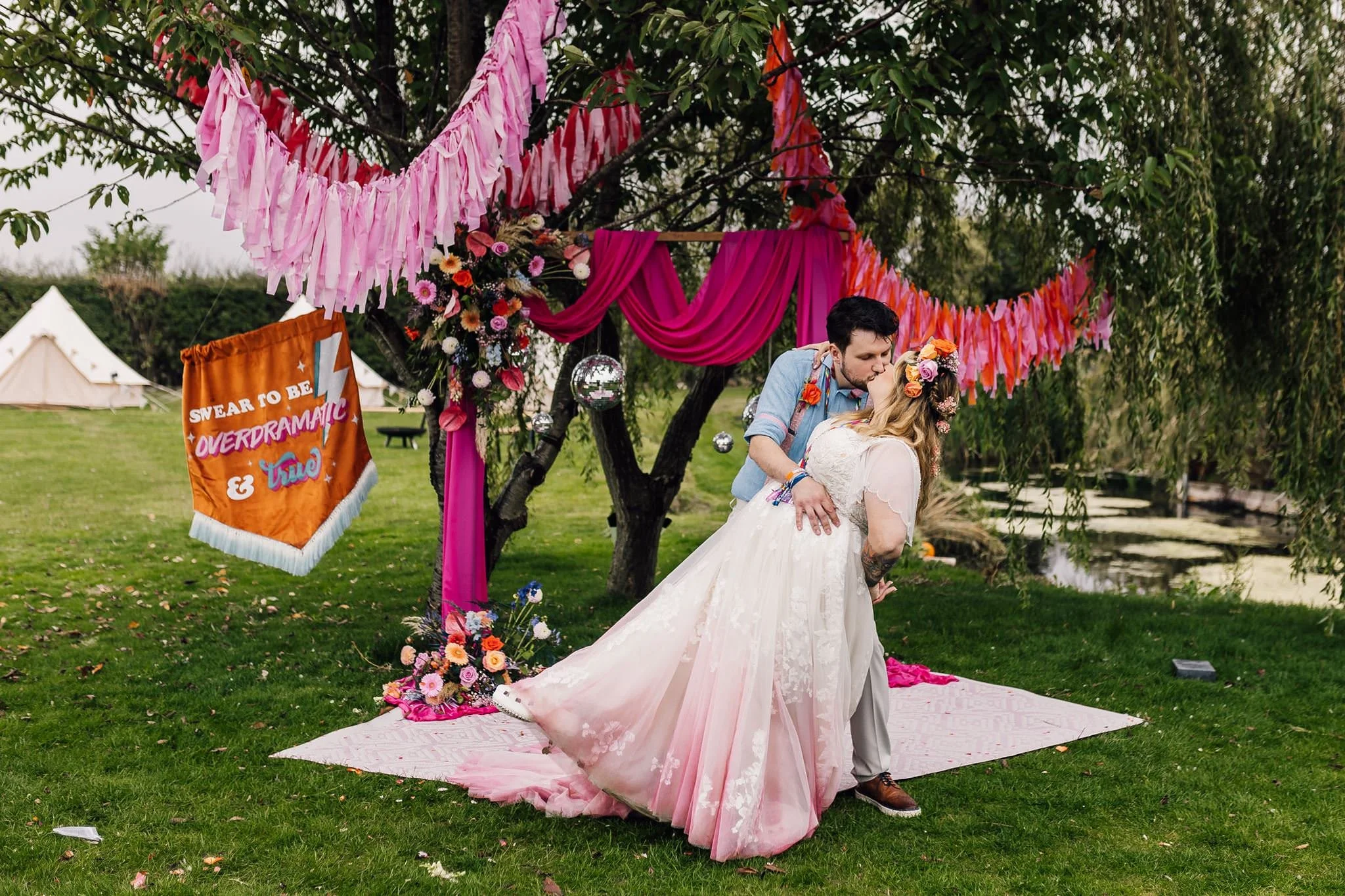 Chloe and Aaron kissing beneath a tree dressed with pink fabric